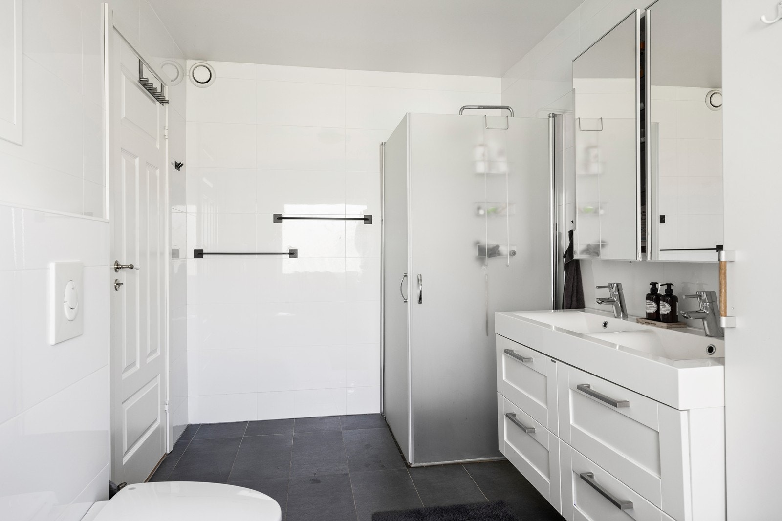 Baderommet inneholder servant på skap, dusjnisje og vegghengt toalett. Galleribilde