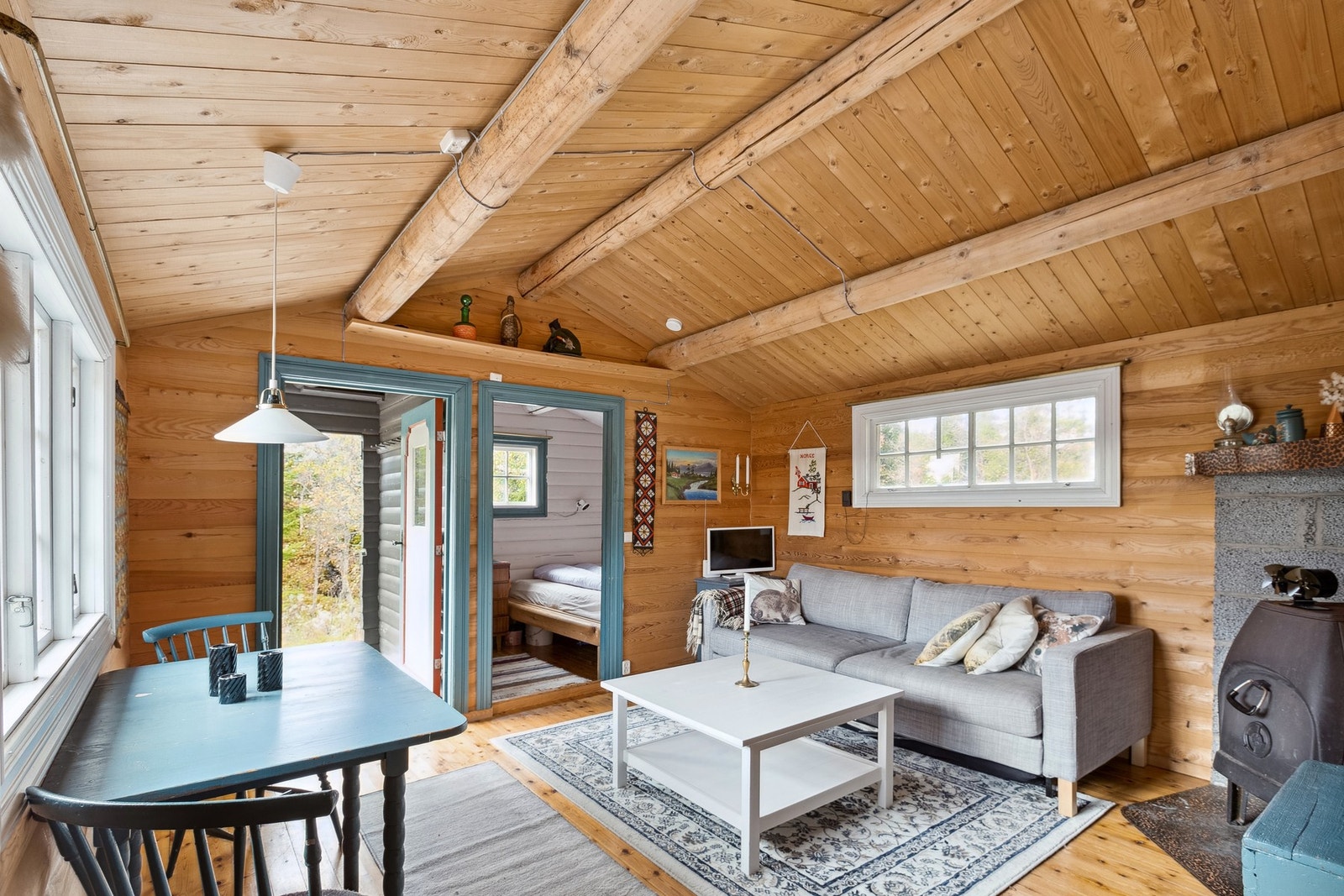 Lys stue med furugulv, tømmervegger og panel i tak. Galleribilde