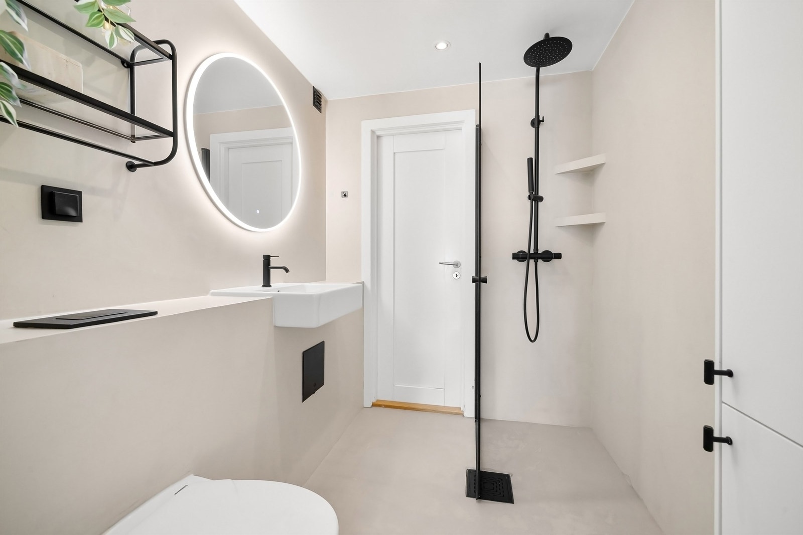 Moderne interiør, regnfallsdusj og vegghengt toalett. Adkomst inn til kjøkkenet fra badet. Galleribilde