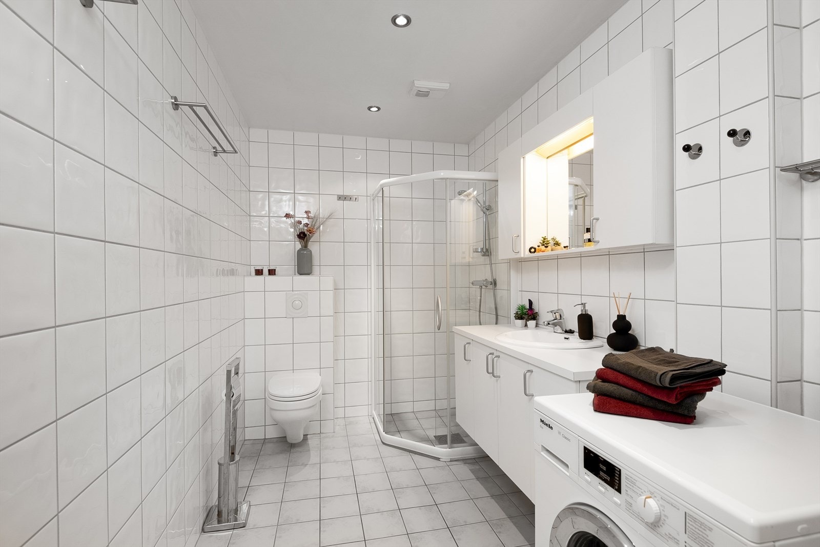 Lyst og flislagt baderom med gulvvarme, innfelte downlights i himling og opplegg for vaskemaskin Galleribilde
