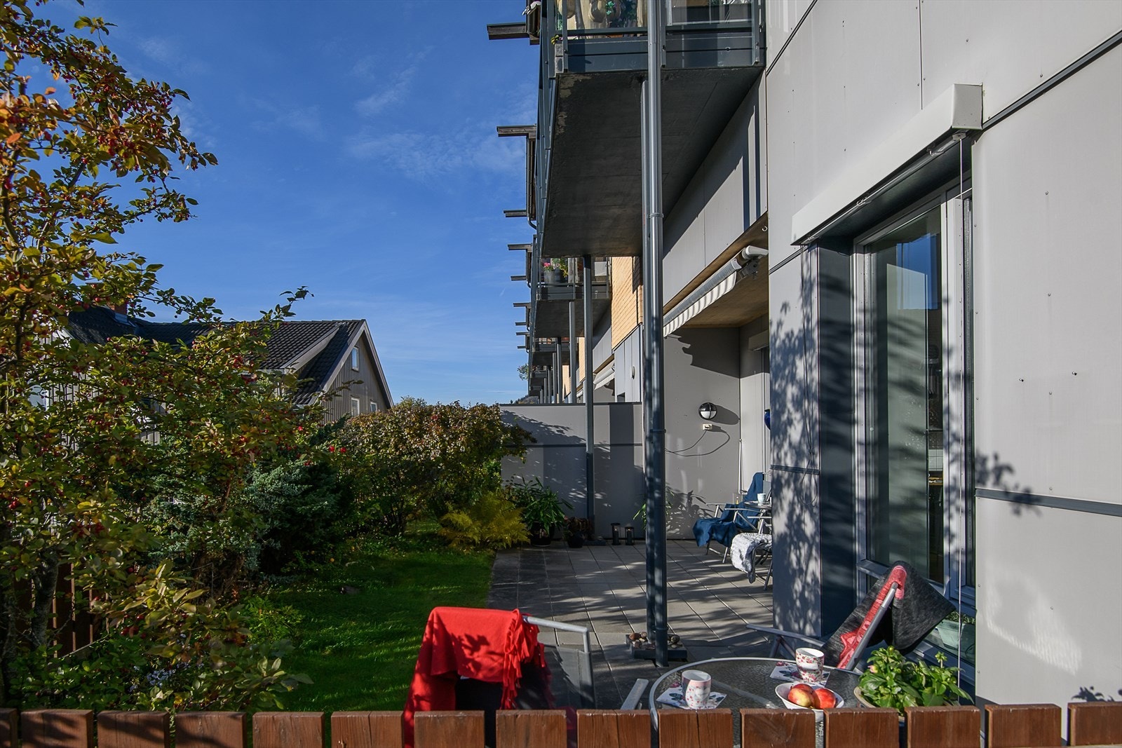 Leiligheten har en solrik uteplass opparbeidet med helleplatting og plenareal Galleribilde