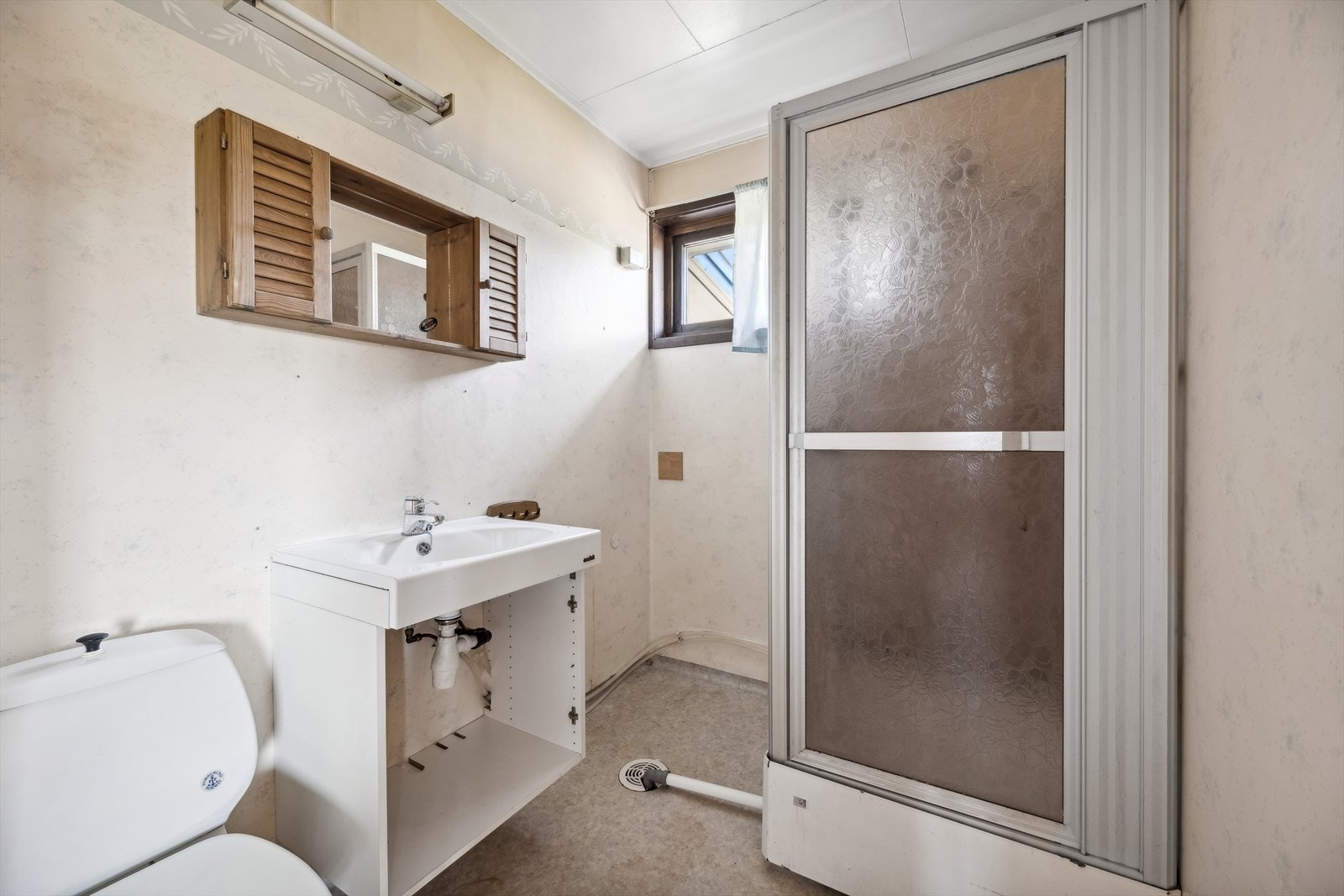 Baderom med dusjkabinett, toalett, servant og speilskap. Galleribilde