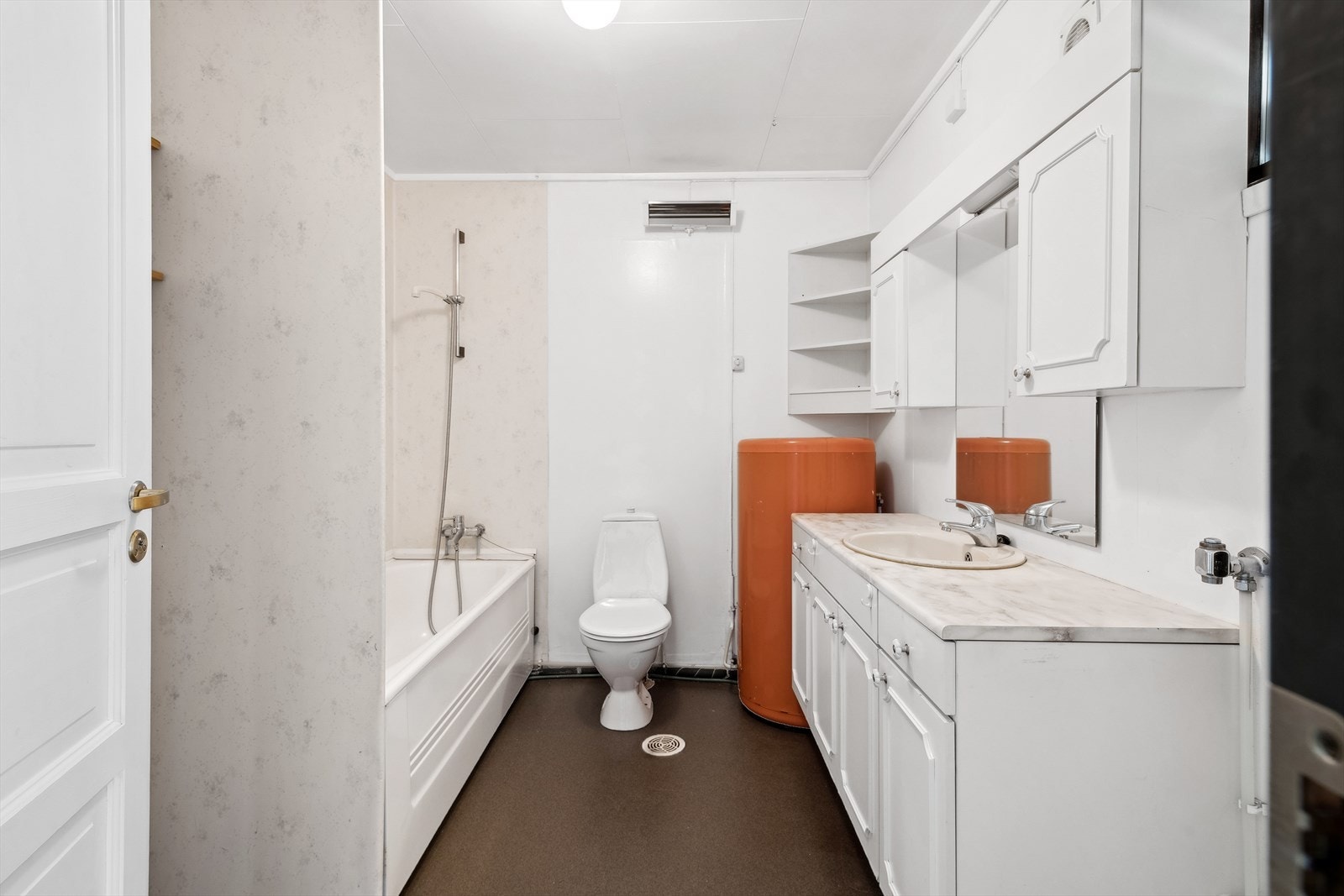 Baderommet er innredet med badekar, toalett, servant over innredning, speilskap og speil. Galleribilde