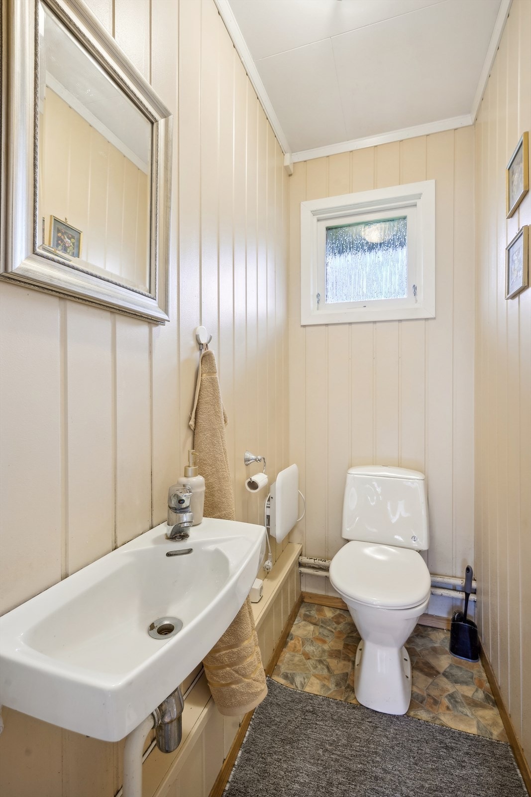 Separat wc-rom med toalett og enkel servant på vegg. Galleribilde