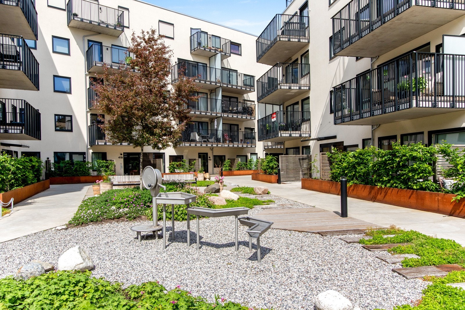 Rundt byggene er det et flott fellesområde med store grøntarealer, trær, benker, gangveier, blomsterbed og stemningsfull belysning. Galleribilde