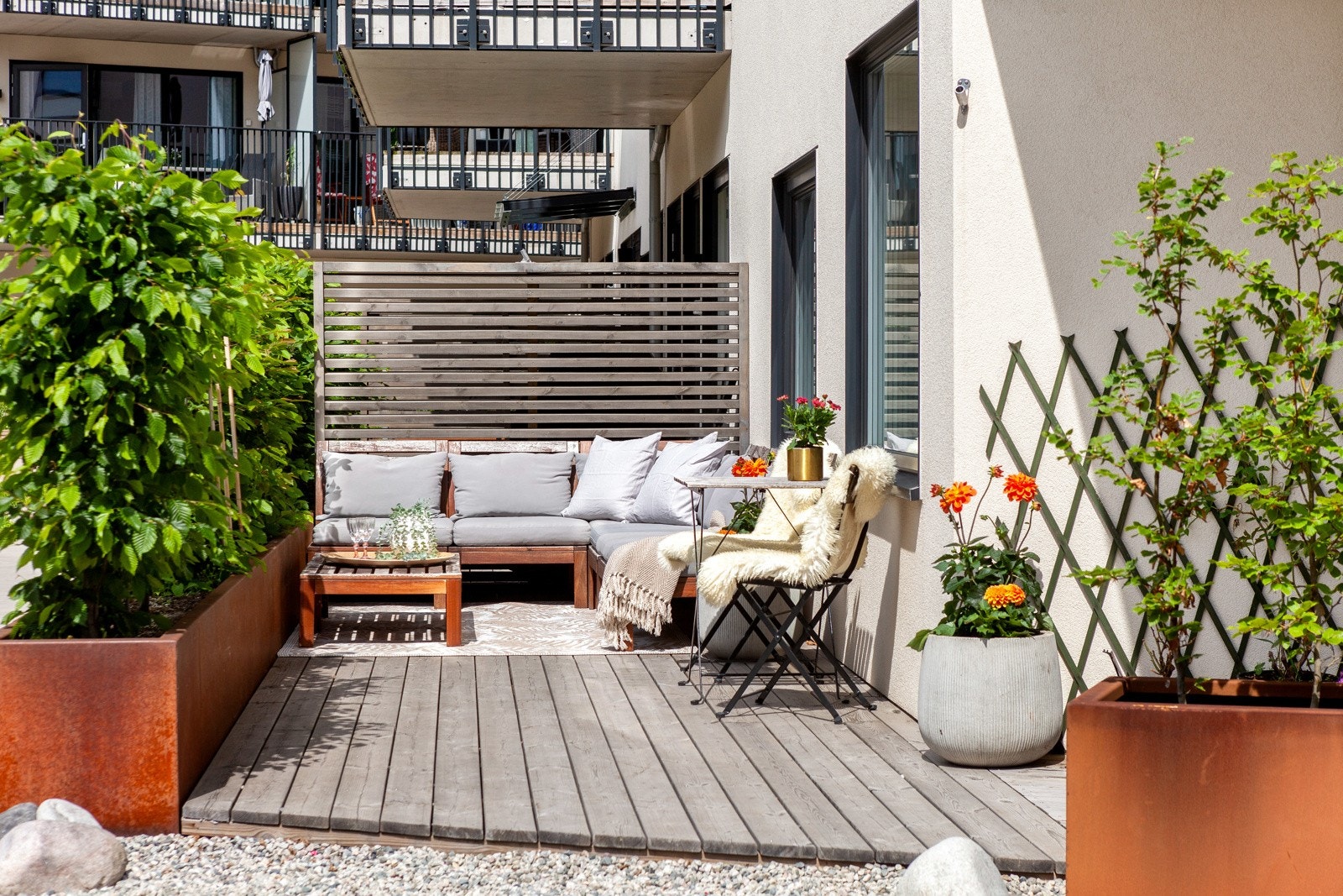 Stor uteplass med to soner og plantekasser med hekkplanter. Galleribilde