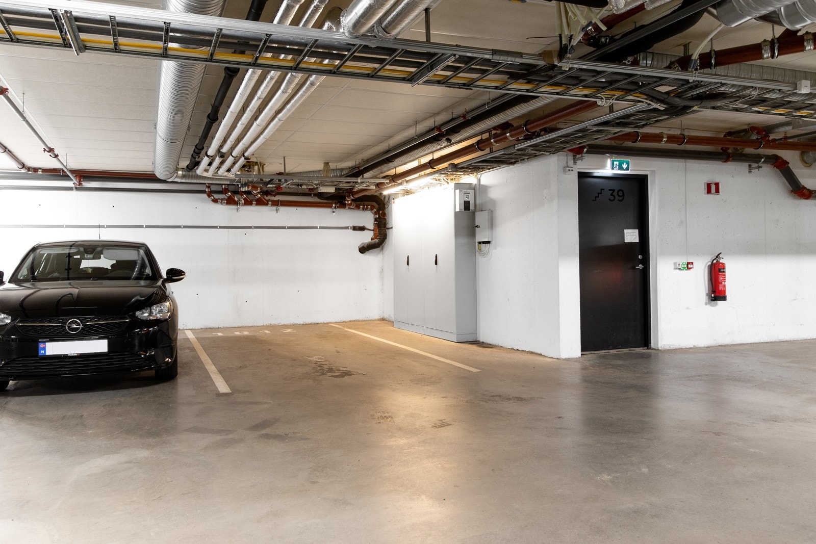 Leiligheten har en garasjeplass med opplegg for lading av elbil i byggets kjeller. Dette er en av garasjens største plasser som sikrer enkel inn- og utkjøring, rett ved siden av oppgangen til leiligheten. Galleribilde