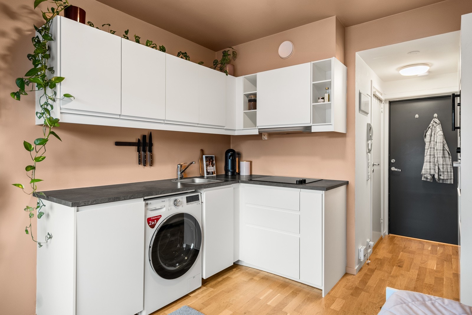 Kjøkkeninnredning med glatte, tidløse fronter - utstyrt med belysning under overskap, benkeplate i laminat med nedfelt kum i rustfritt stål, stekeovn, platetopp, oppvaskmaskin og kjøl/frys. Galleribilde