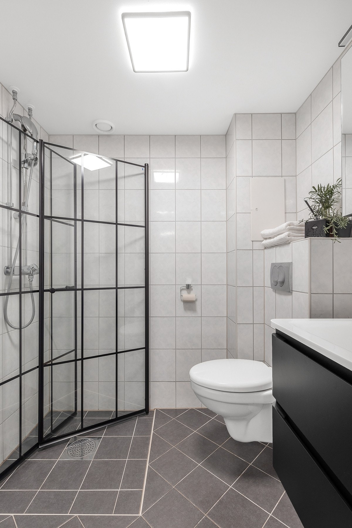 Rommet er utstyrt med vegghengt servantinnredning, speilskap, dusjhjørne og vegghengt toalett Galleribilde