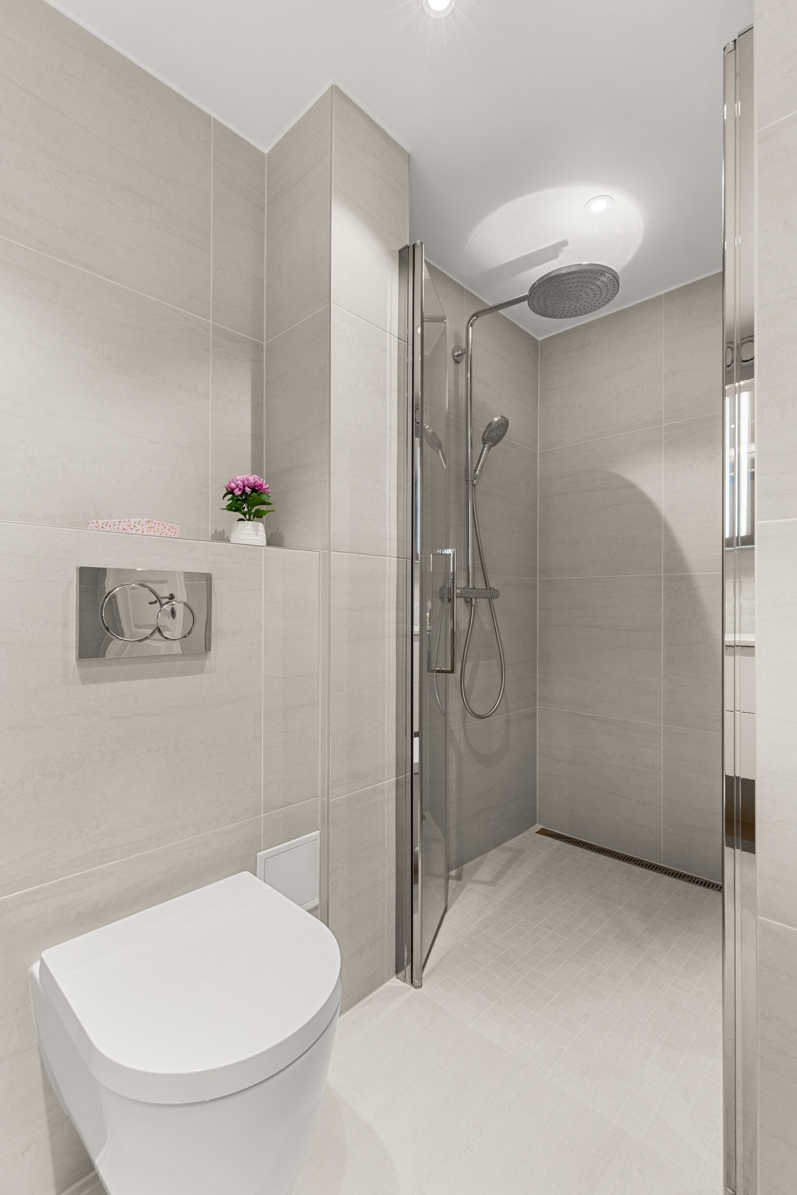 Vegghengt toalett, dusjnisje med svingbare glassdører og regndusj fullfører det moderne inntrykket. Galleribilde