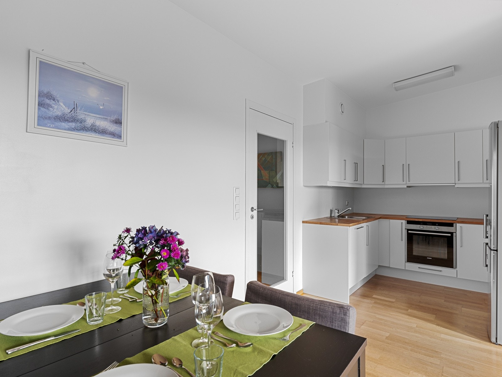 Kjøkkenet ligger i en krok for seg selv i åpen løsning til stuen Galleribilde