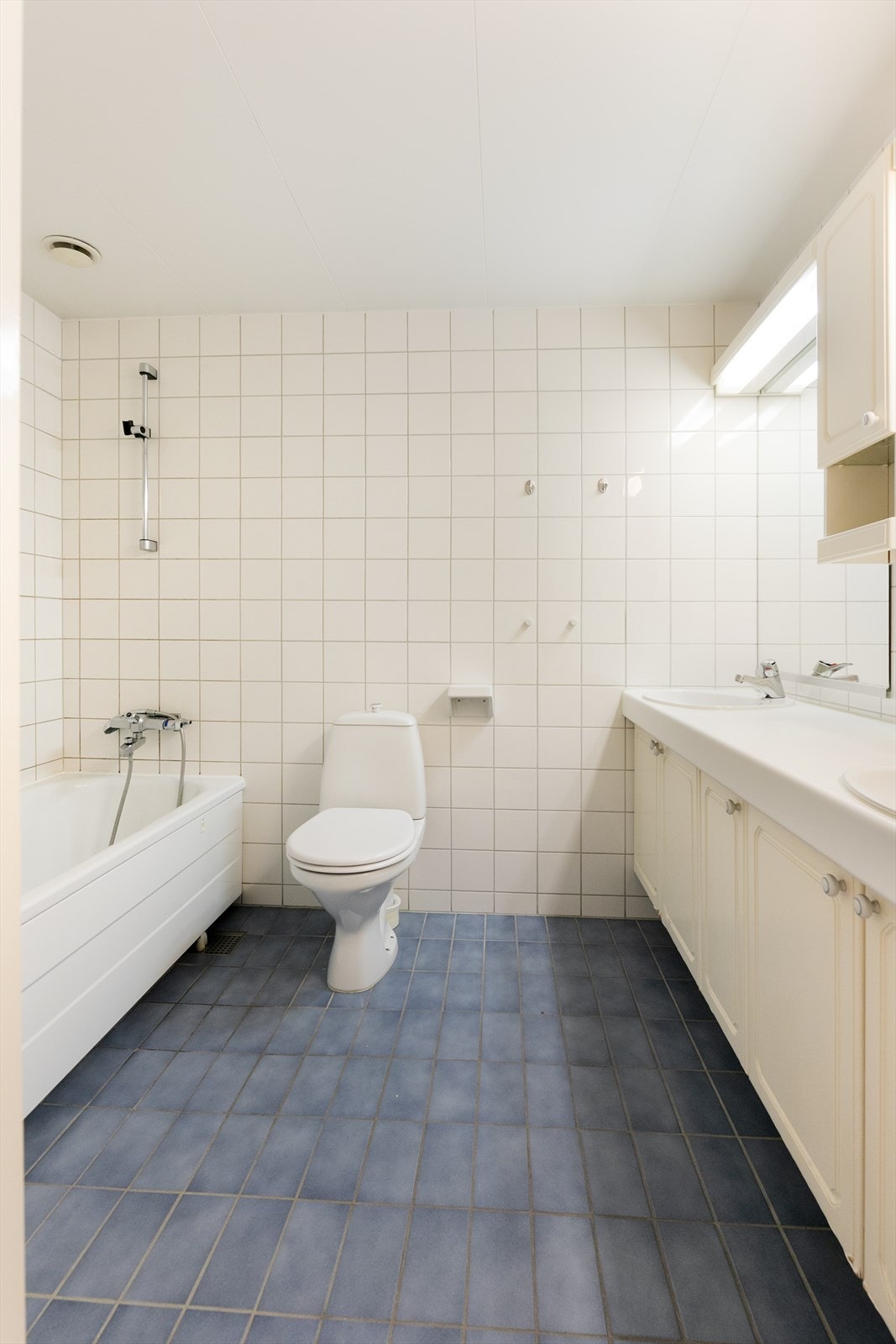 Flislagt bad med varmekabler i gulv, frittstående badekar og gulvmontert toalett Galleribilde