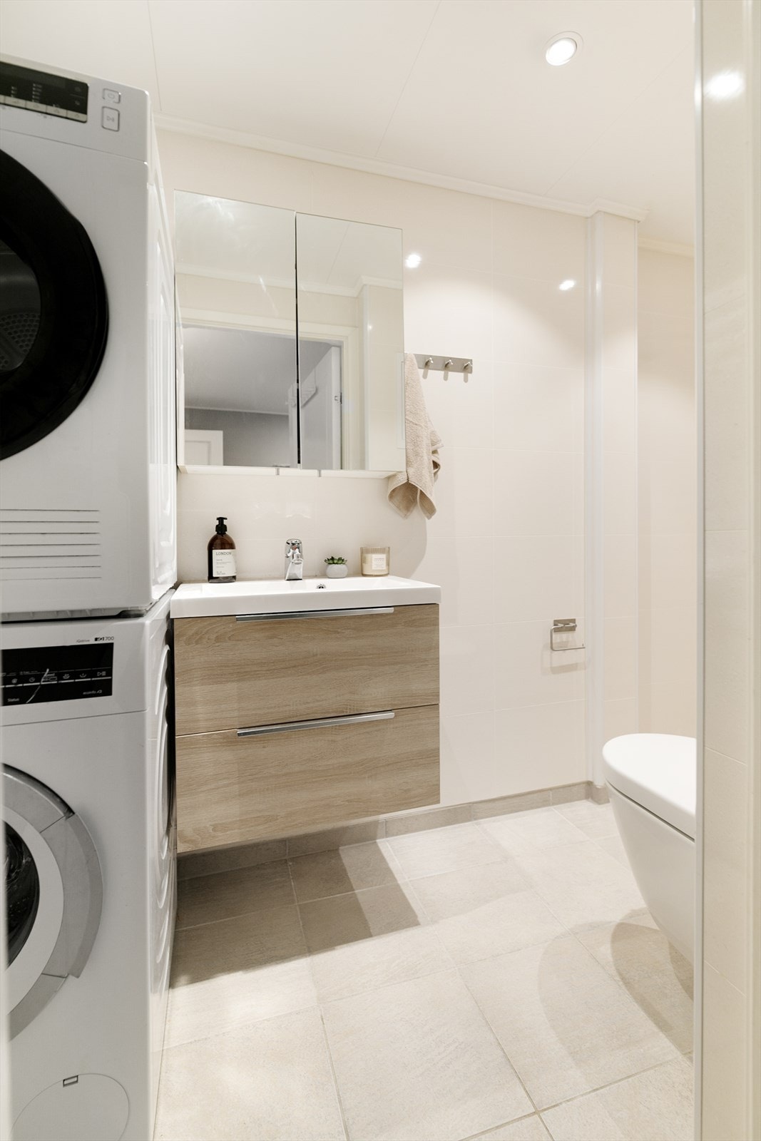 Flislagt bad i 1.etg med varmekabler i gulv, servantseksjon med skuffer og overskap med speilfronter - og opplegg for vaskemaskin Galleribilde