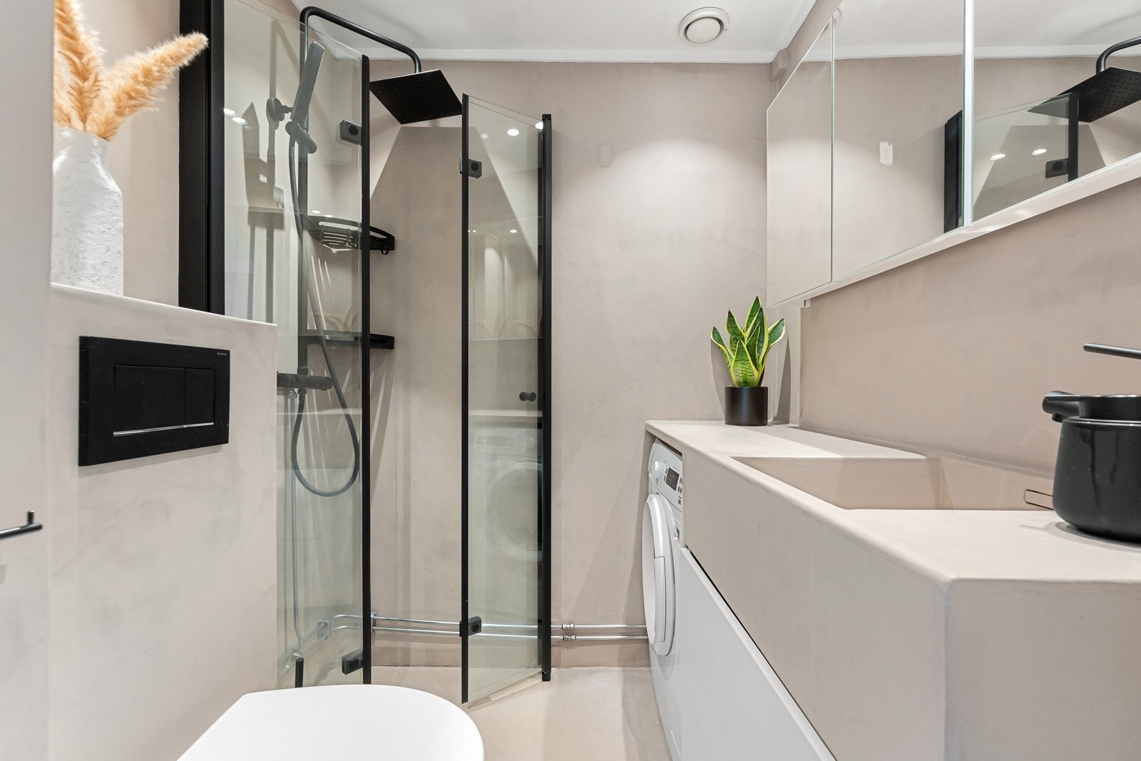 Delikat og flislagt baderom som består av dusjhjørne, servant over innredning, vegghengt toalett og speilskap. Galleribilde