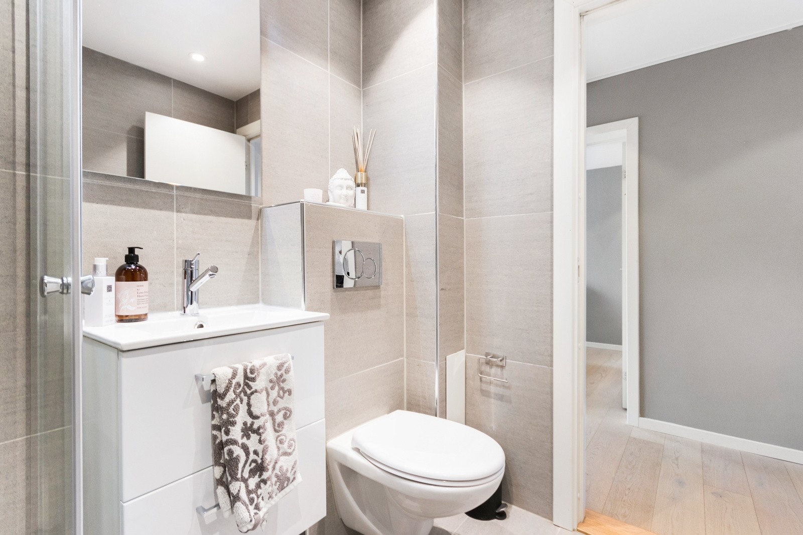 Innredningen består av servantskap med skuffer, i hvit glatt utførelse med heldekkende servant, speil, vegghengt toalett og dusjhjørne med skyvedører. På badet er det opplegg for vaskemaskin. Galleribilde