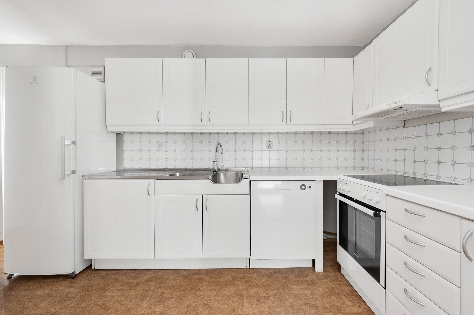 Kjøkkeninnredning fra byggeår med profilerte, lyse fronter og benkeplate av laminat. Galleribilde