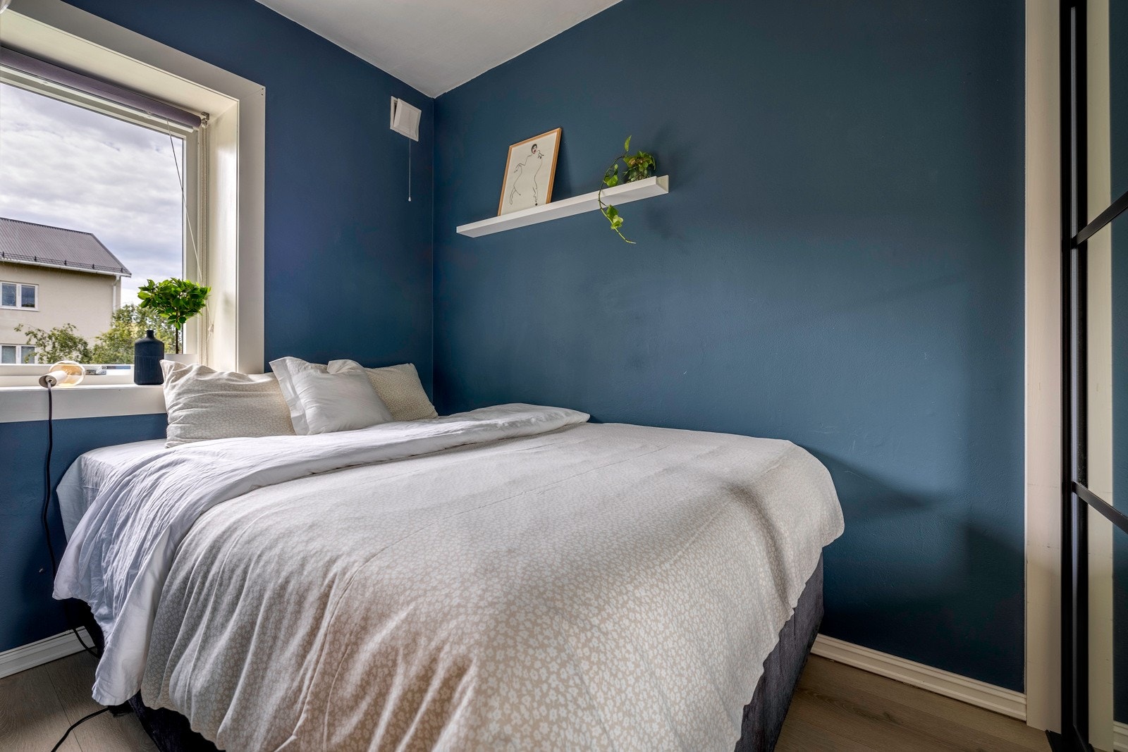 Soverommet i leiligheten er malt i en harmonisk og behagelig blåfarge som skaper en lun og avslappende atmosfære Galleribilde