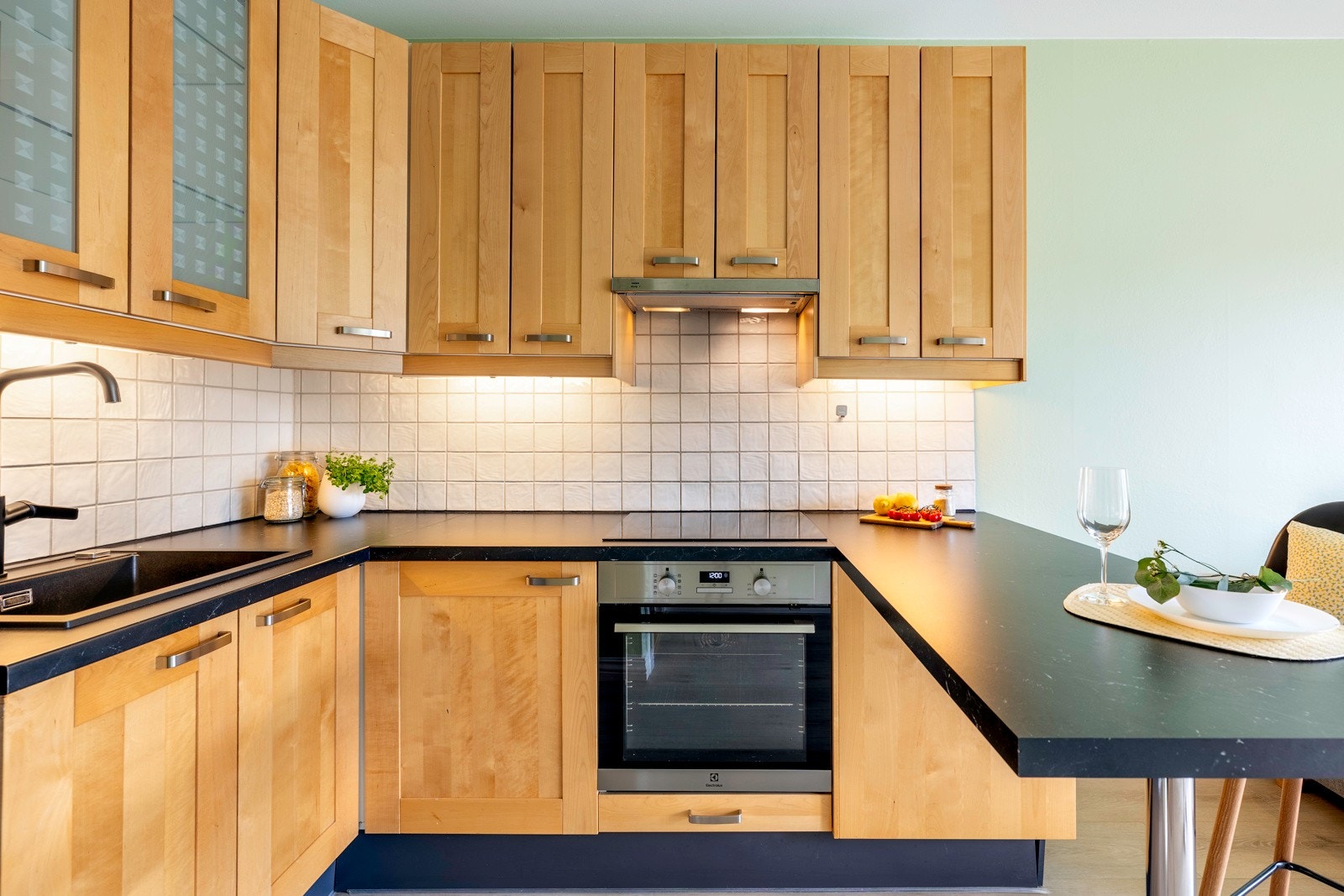 Mellom benkeplaten og overskapene er det flislagt, noe som både beskytter veggen og gir en stilfull finish. Galleribilde