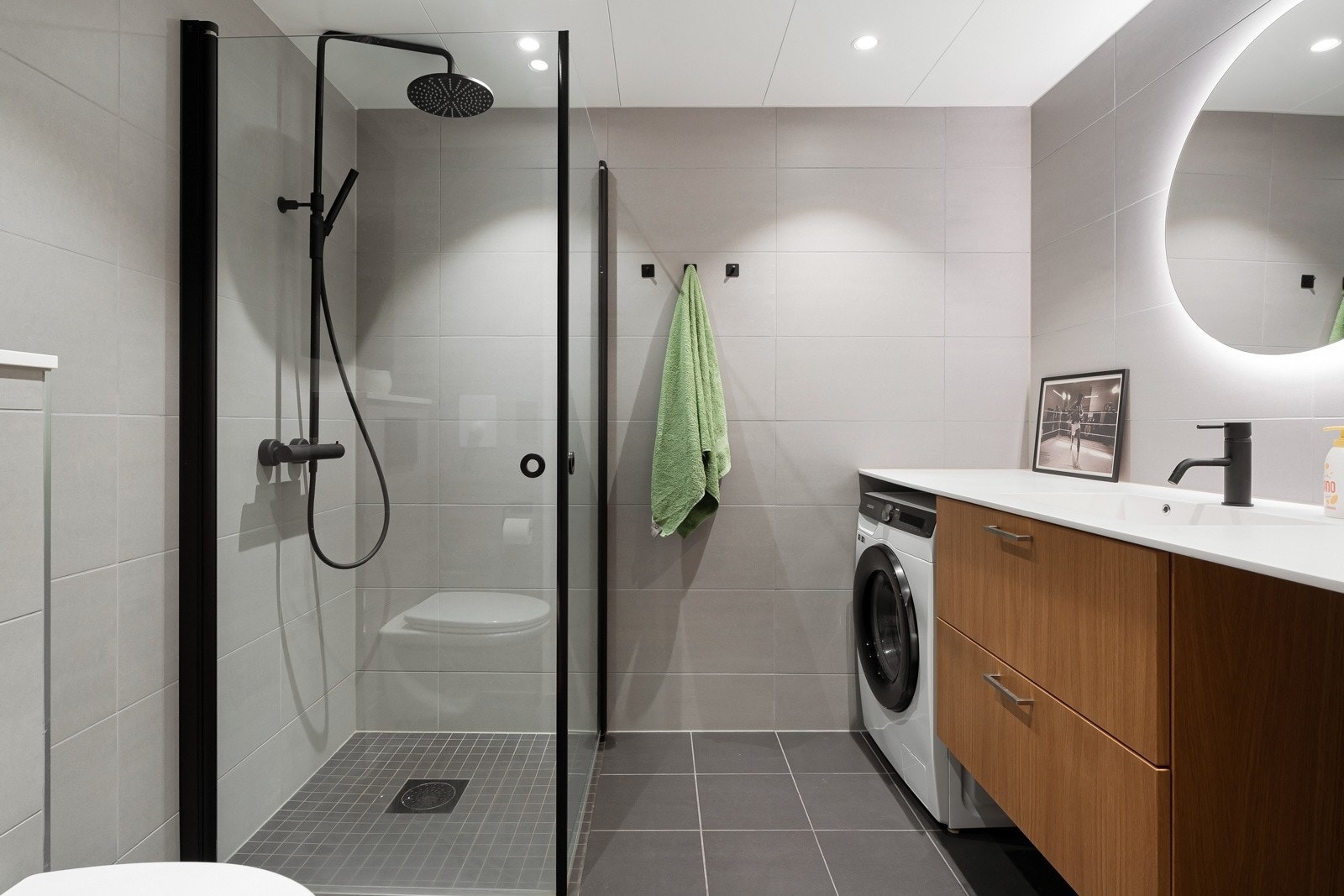 Delikat og flislagt baderom som består av dusjhjørne, servant over innredning, vegghengt toalett og speil. Galleribilde