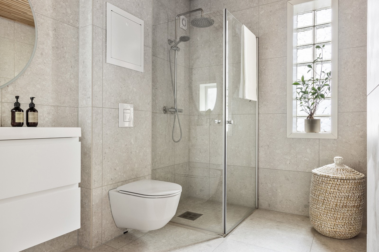 Badet er innredet med dusj med glassvegger, vegghengt toalett, baderomsinnredning og opplegg for vaskemaskin. Galleribilde