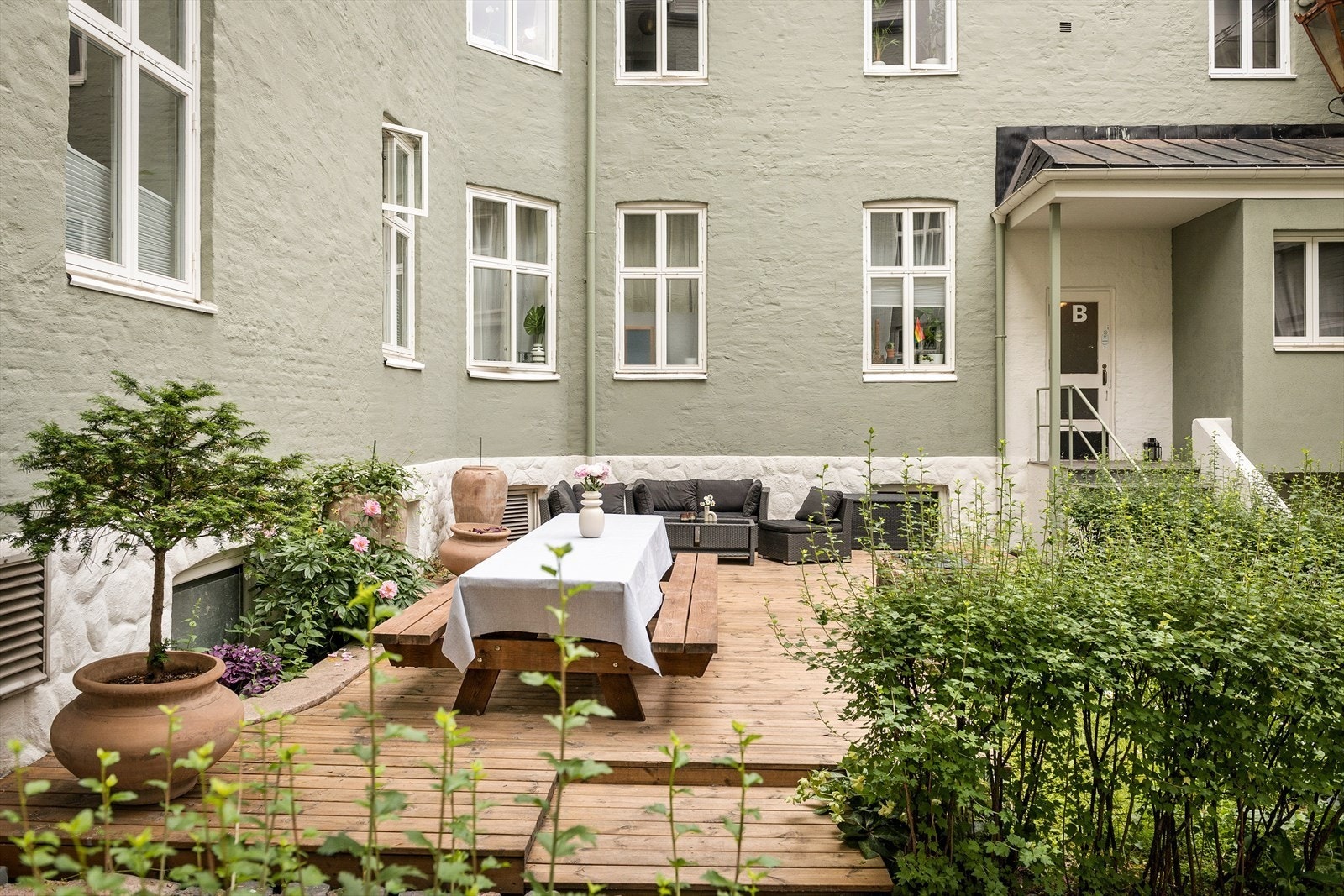 Stor terrasseplatting i bakgård i frodige omgivelser. Galleribilde