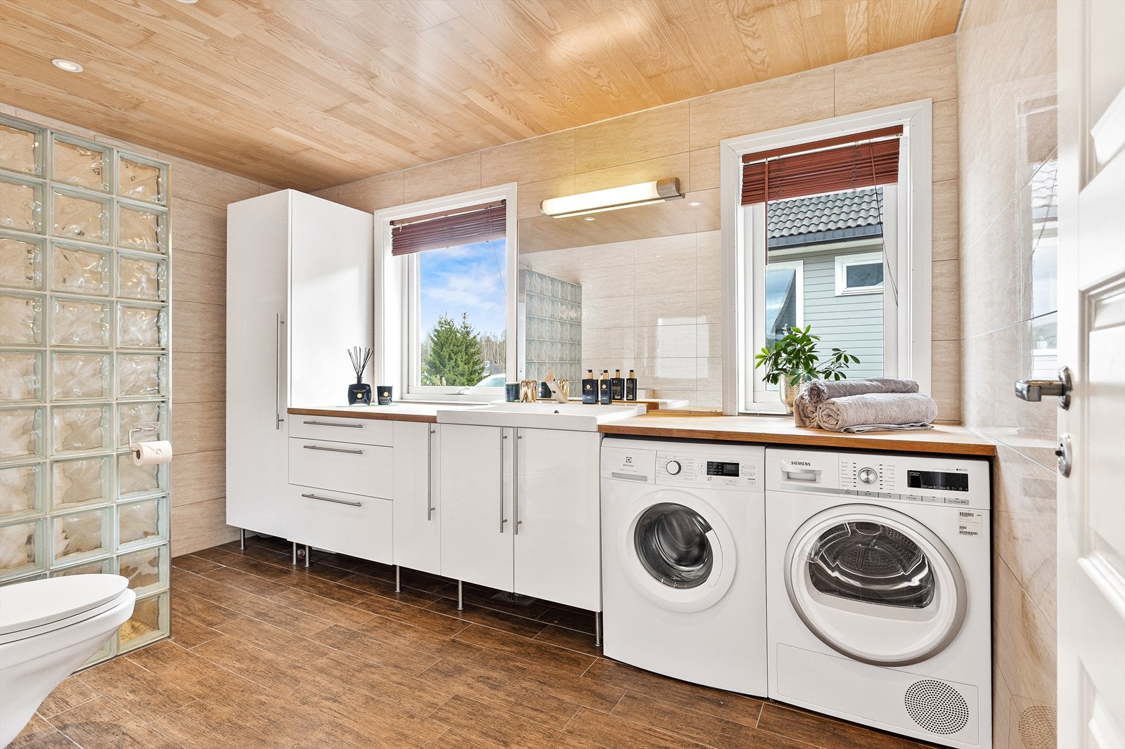 Opplegg og plass til både vaskemaskin og tørketrommel under praktisk brettebenk. Galleribilde