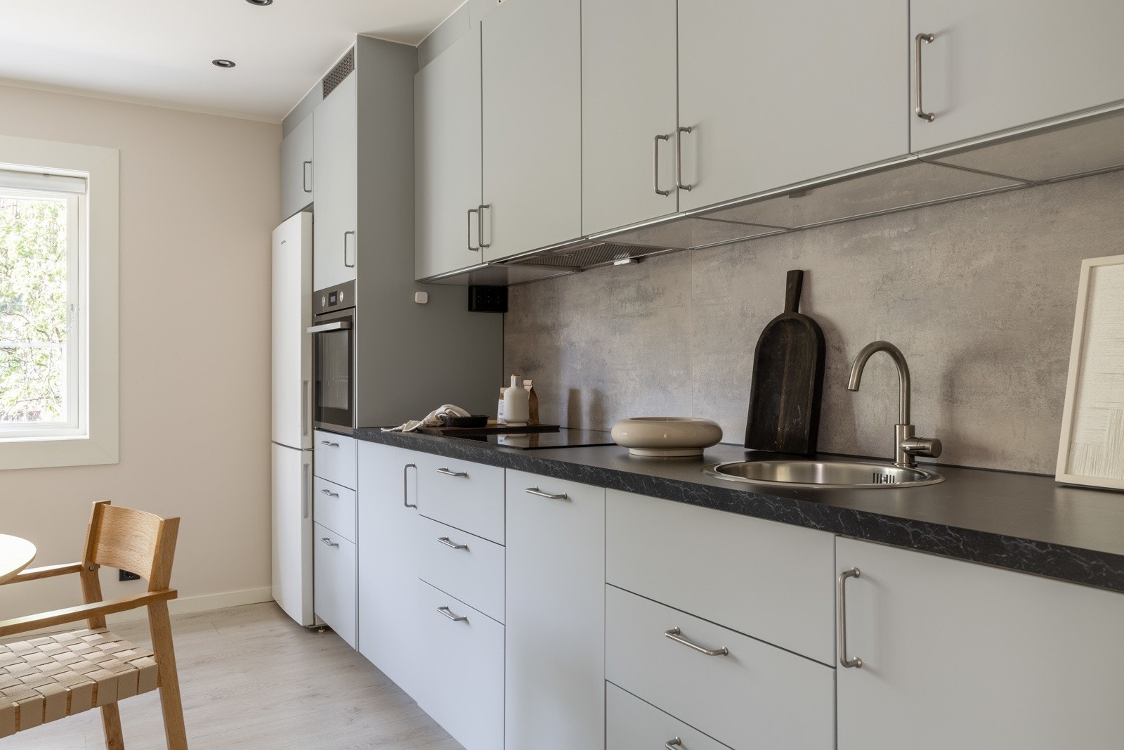 Leiligheten har et stilrent og arbeidsvennlig kjøkken fra 2023 som er i en sosial planløsning med stuen. Galleribilde