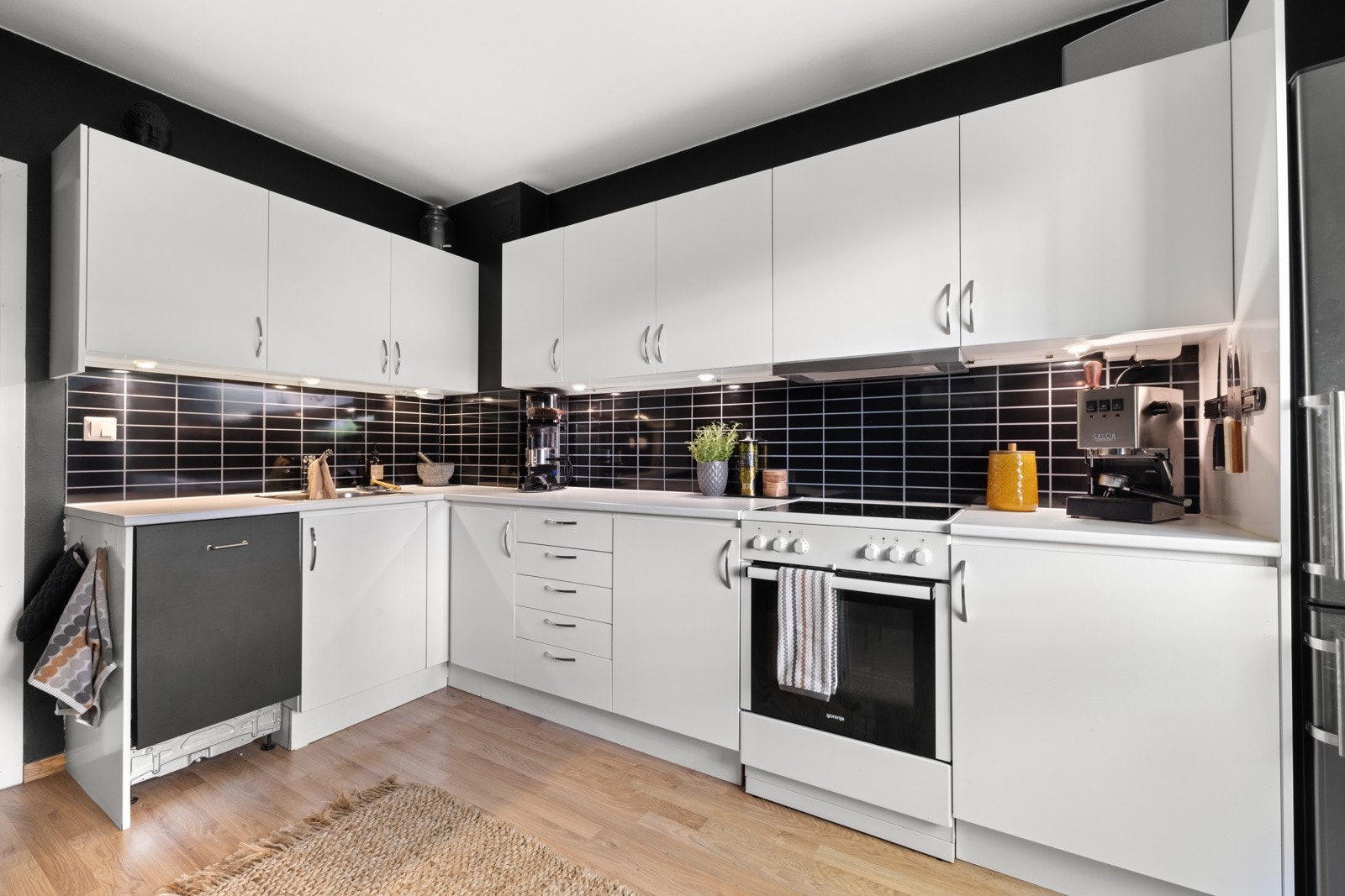 Innenfor entreen har leiligheten et fint kjøkken med lyst laminatgulv og veggflater malt i sort for en fin kontrast Galleribilde