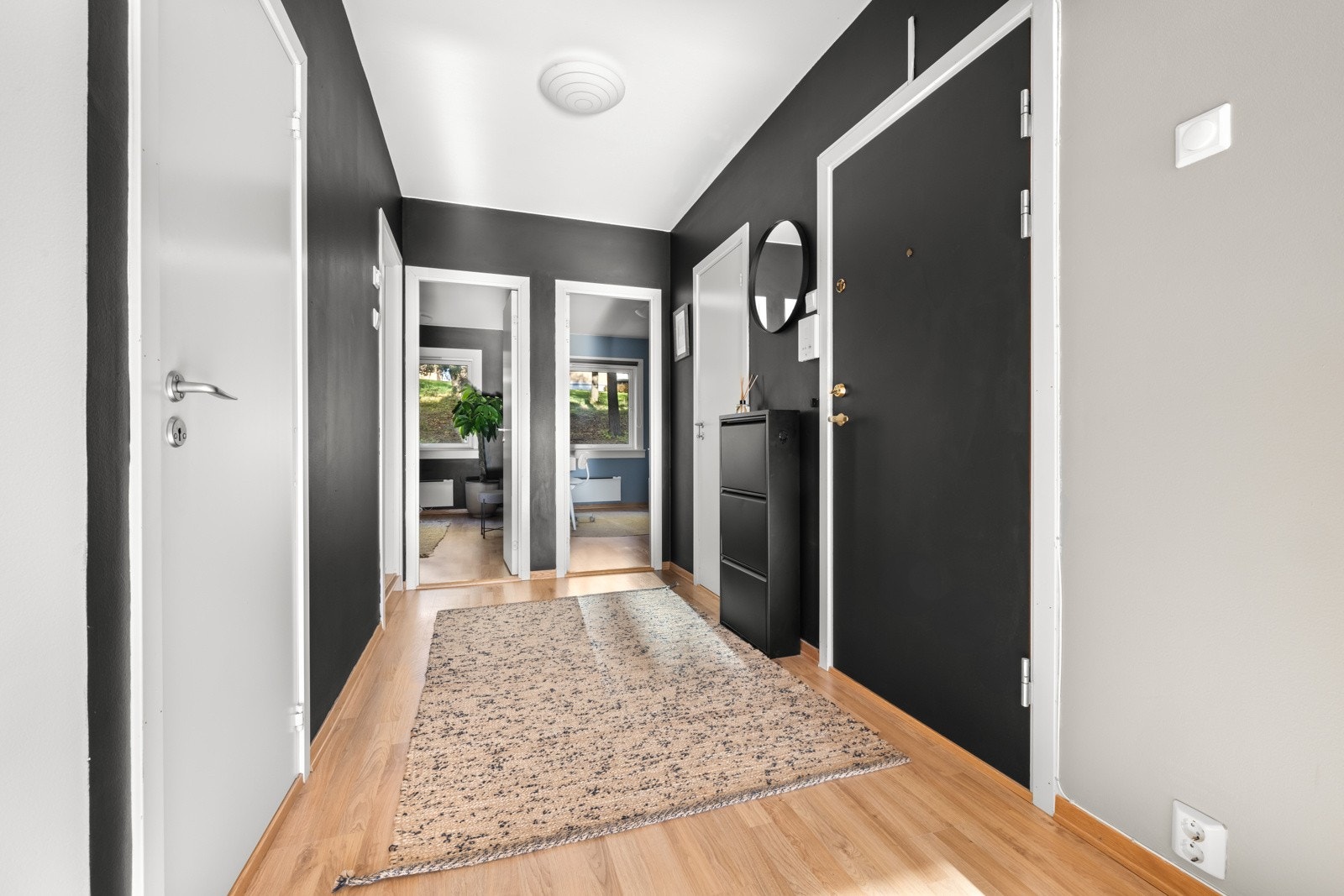 Vel inne ønskes man velkommen av en innbydende entré, der laminatgulv kombineres med veggflater malt i sort og lysegrått Galleribilde