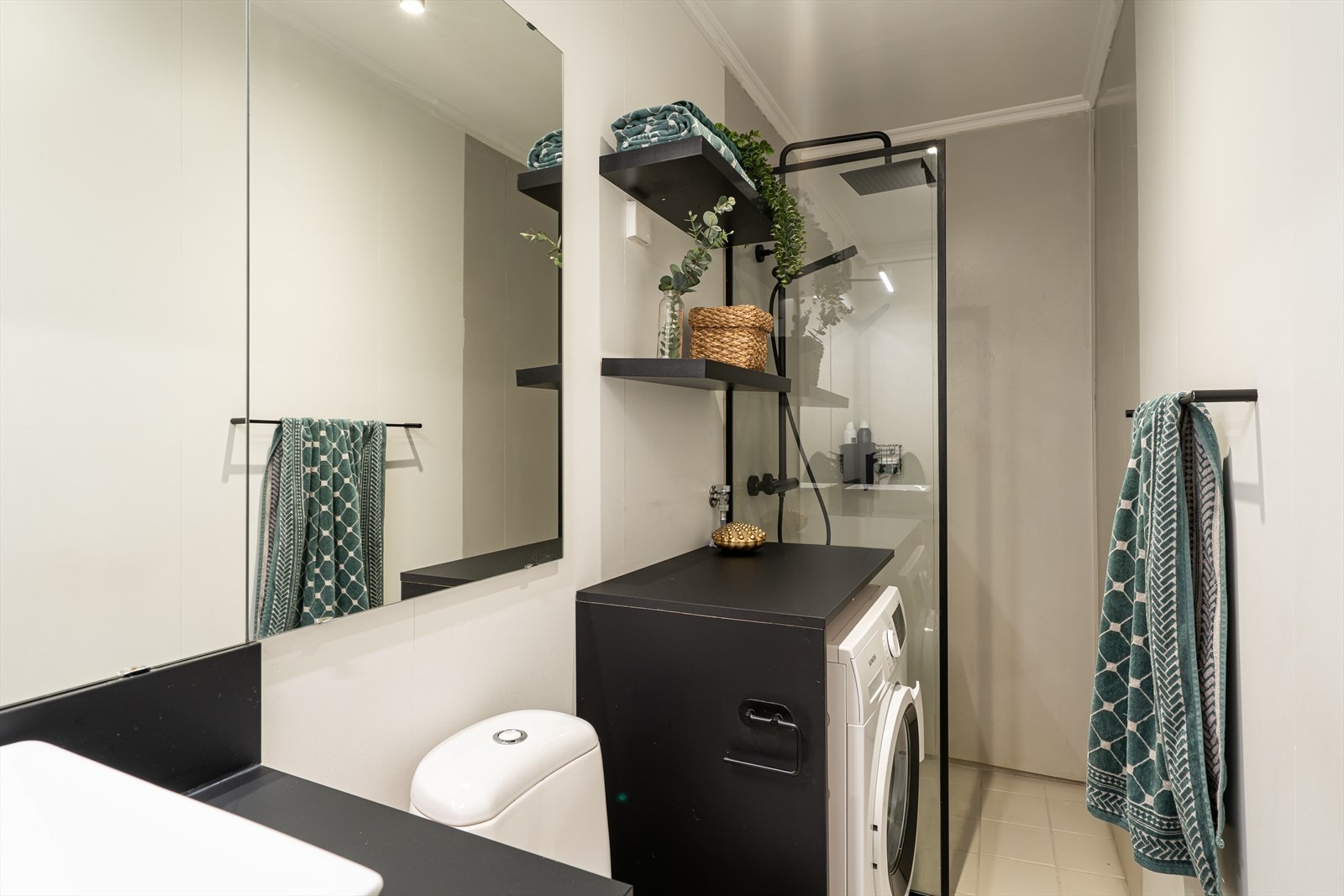 Dusjnisje med glassvegg, gir en smart utnyttelse av plassen. Speilskap og servantskap gir god oppbevaringsplass, og det er opplegg for vaskemaskin. Galleribilde