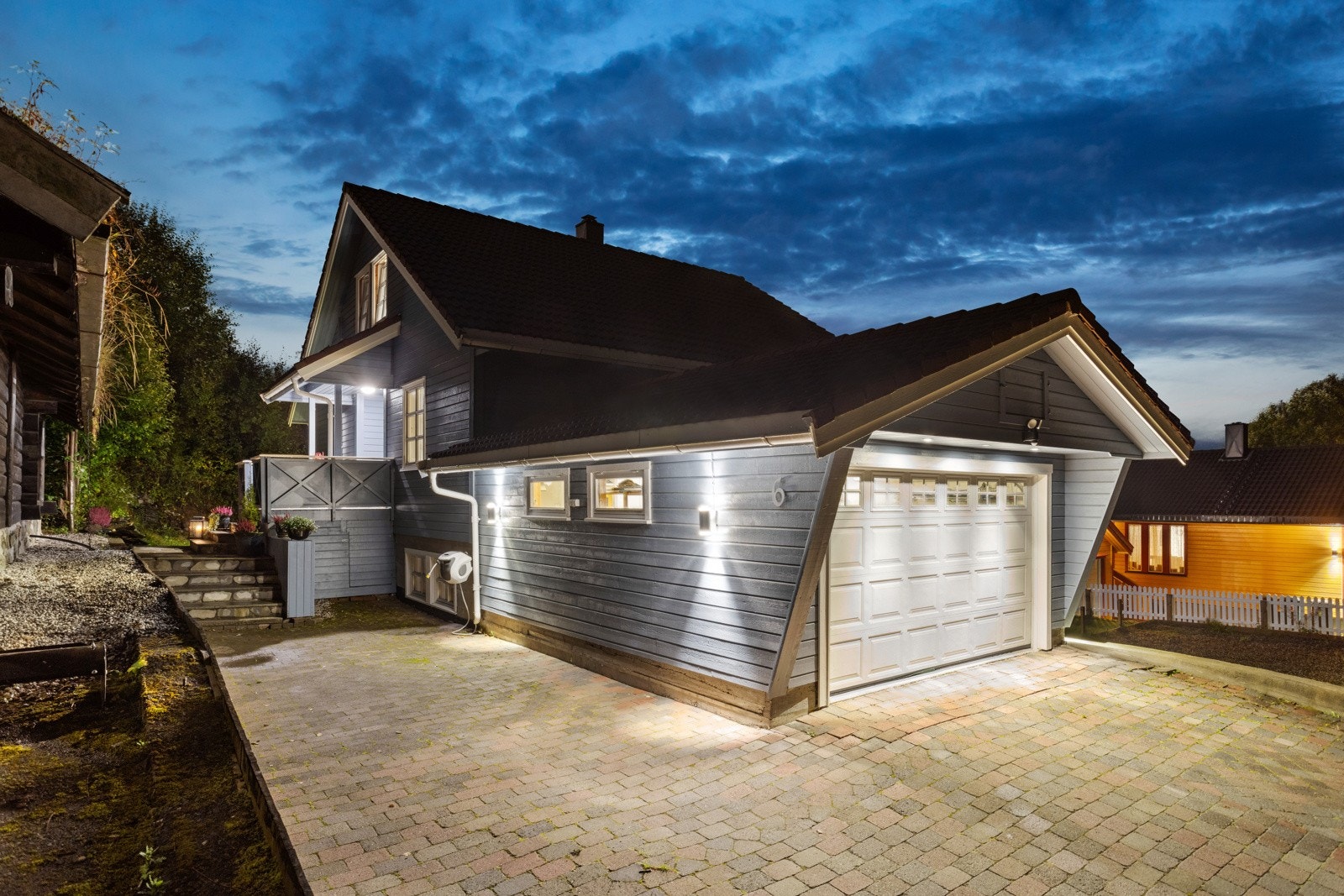 Boligen har en stor, steinbelagt gårdsplass med integrert garasje. Galleribilde