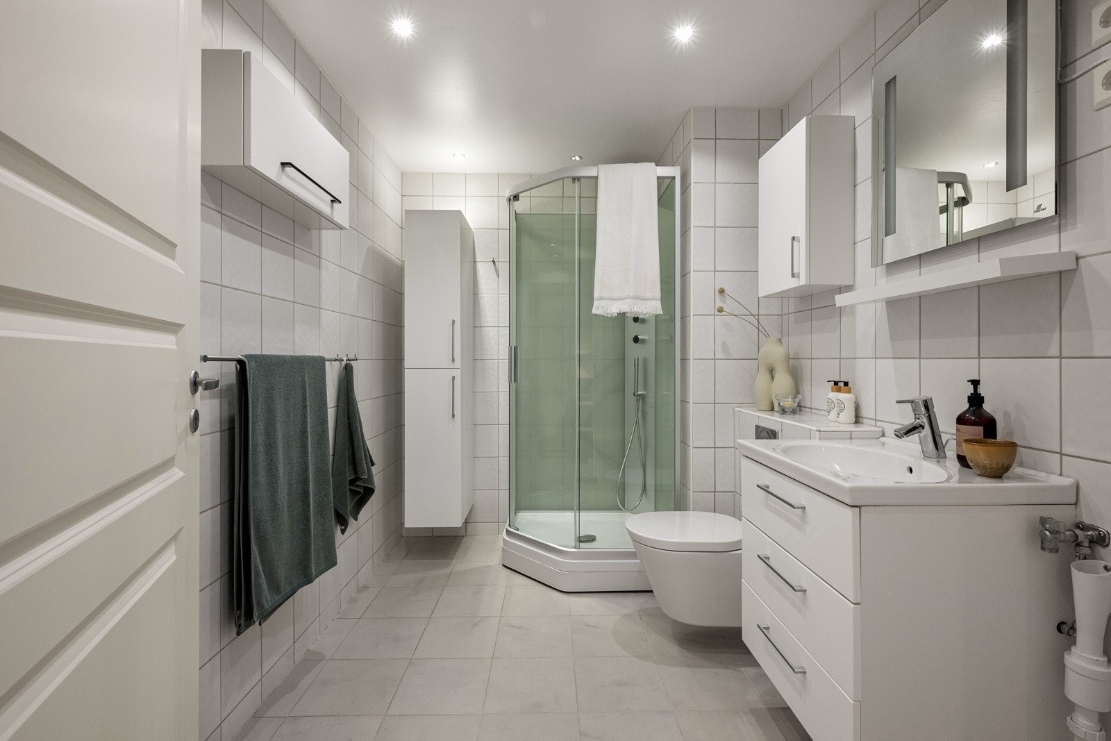 Fint bad med flislagte overflater, servantinnredning, dusjkabinett, vegghengt toalett og opplegg for vaskemaskin og tørketrommel. Galleribilde