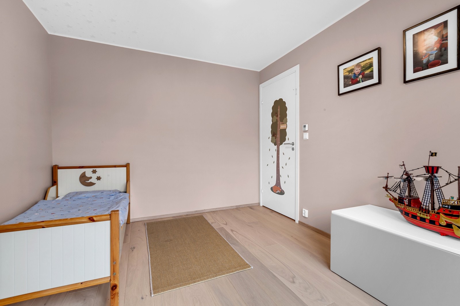 Soverom 2 har samme parkett på gulv og er malt i samme lyse rosa farge på veggene, der en av veggene er hvitmalt. Galleribilde