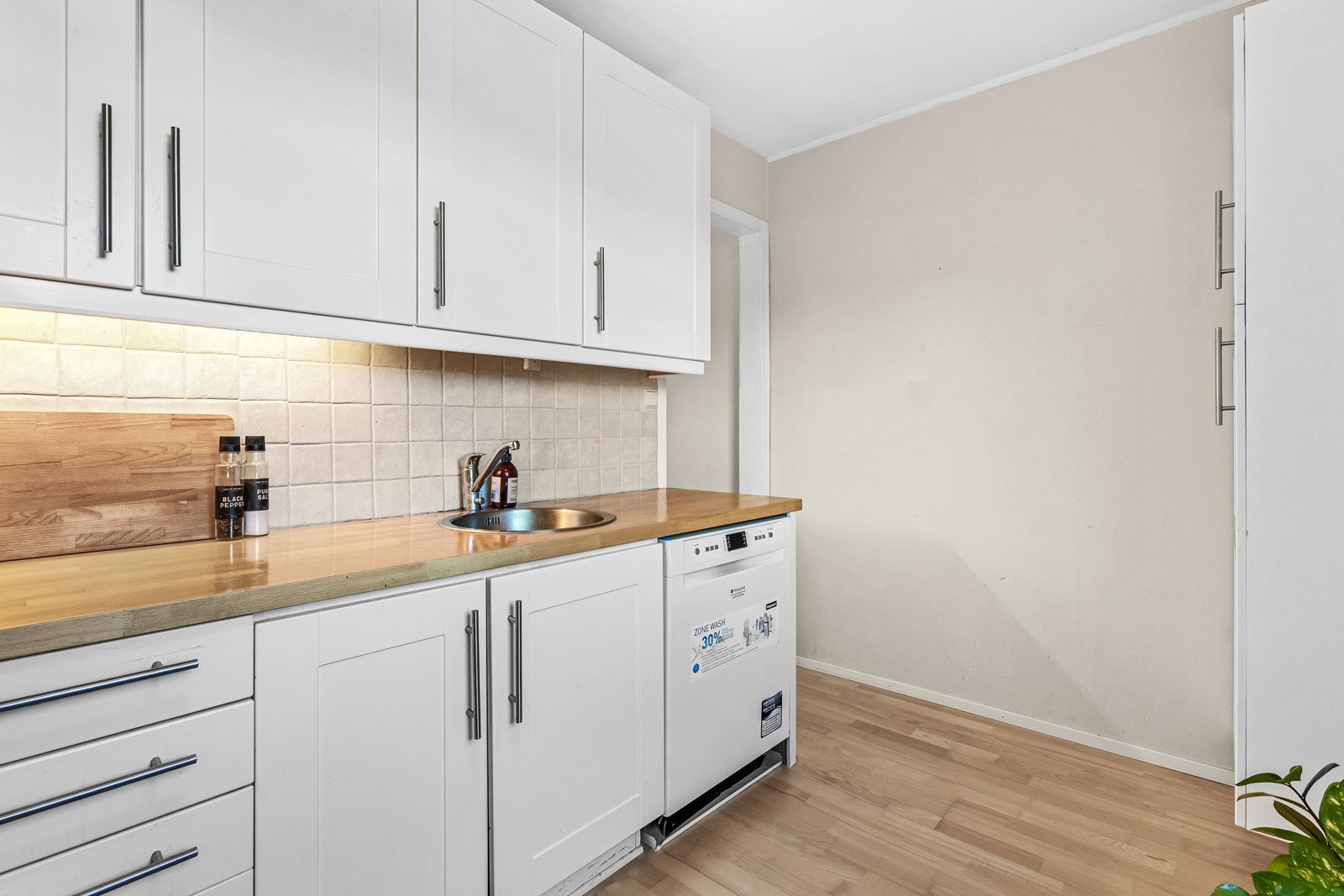 Videre har kjøkkenet nisje for komfyr, ventilator i overkant, avsatt plass til kjøleskap og opplegg for oppvaskmaskin. Galleribilde