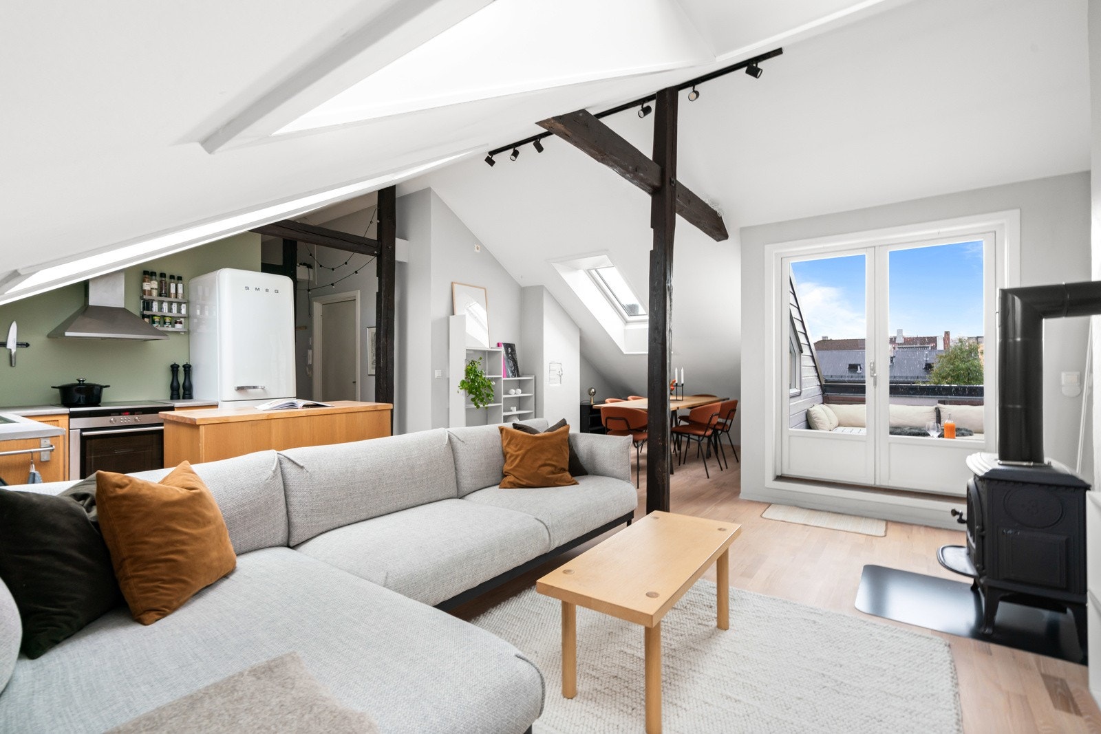 Stuen har en delikat miks av klassisk og moderne, der synlige trebjelker kombineres med parkettgulv og veggflater malt i lysegrått og en dus grønntone. Galleribilde