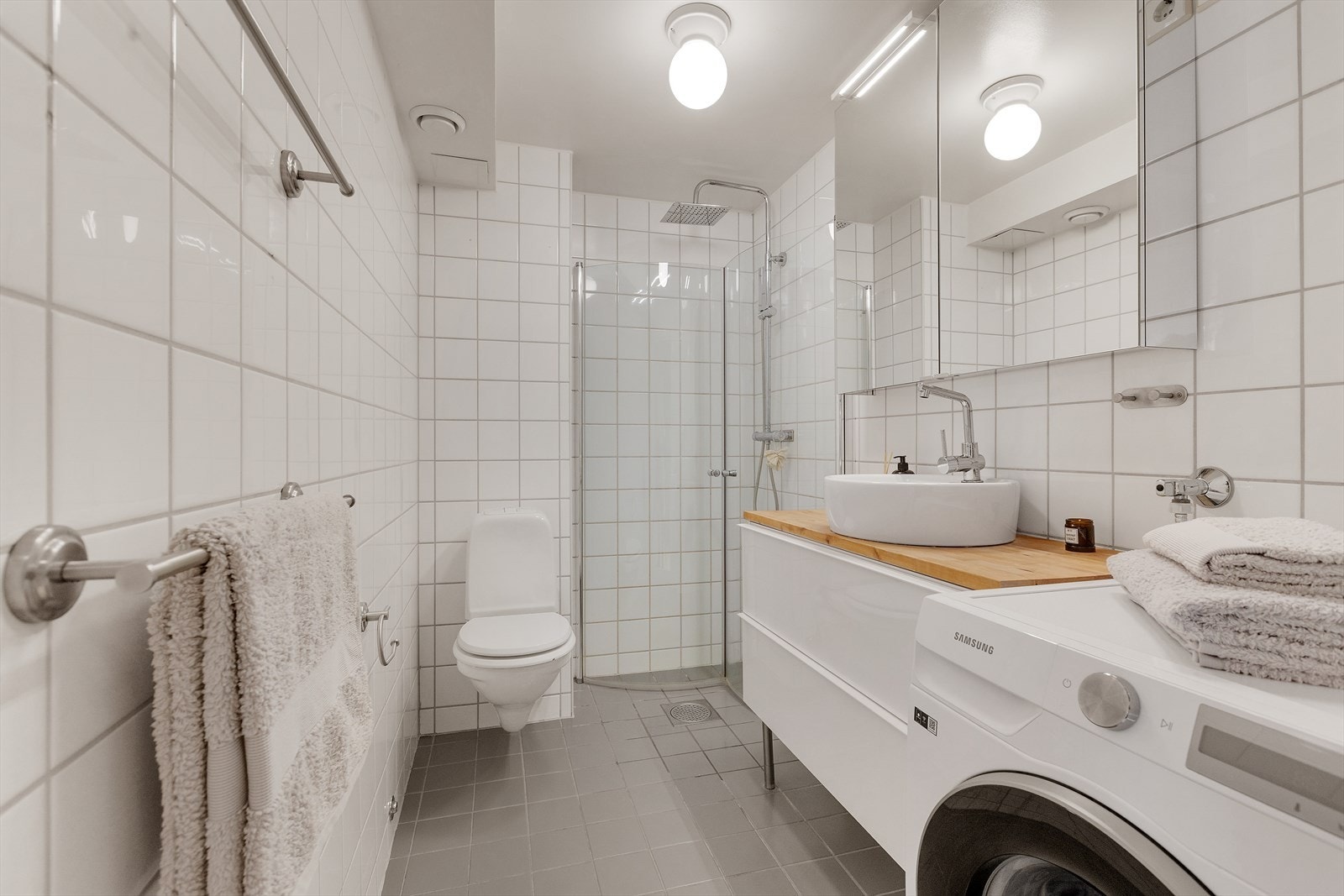 Leiligheten har et pent og lyst baderom med elektrisk gulvvarme. Badet har et romslig dusjhjørne med innfellbare glassdører, samt vegghengt toalett. Galleribilde