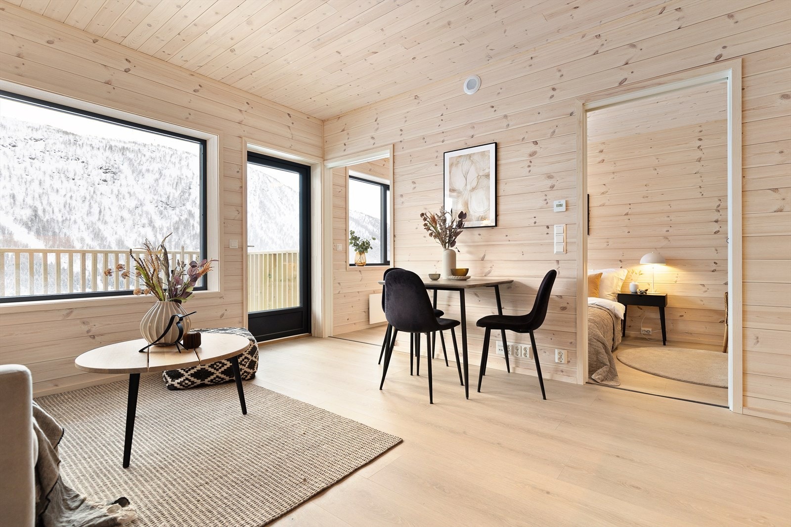 Entréen fører inn til stue og kjøkken i åpen løsning. Her er det de store vindusflatene og utgang til balkong som trekker oppmerksomhet, rammet inn av hvitlasert panel på vegger og tak. Bilder er tatt av en annen leilighet. Galleribilde