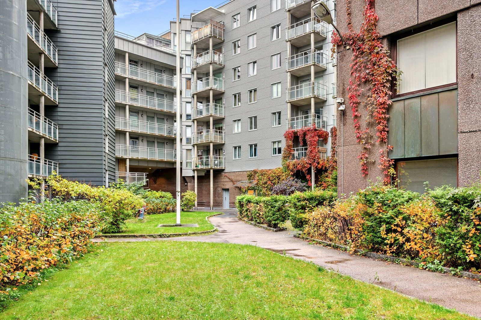 Flotte uteområder i borettslaget med grøntarealer, beplantning og busker samt asfalterte internveier. Galleribilde