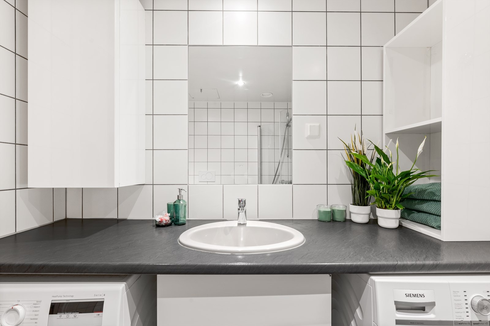 Lyst, flislagt bad med plass til både vaskemaskin og tørketrommel under benkeplate. Galleribilde