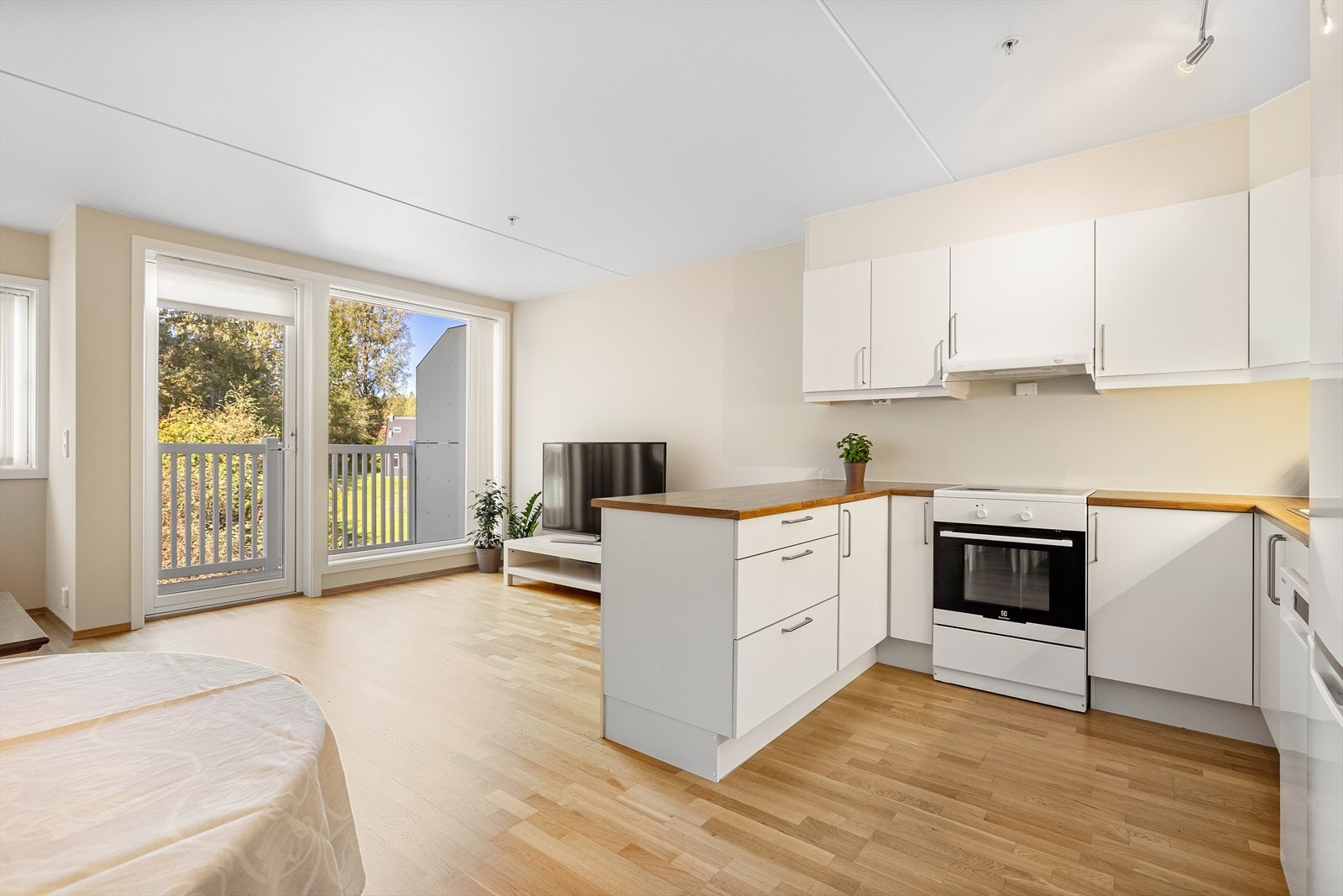 Tidløst Sigdal-kjøkken fra 2015 med hvite laminerte fronter og benkeplate i laminat. Frittstående hvitevarer. Galleribilde