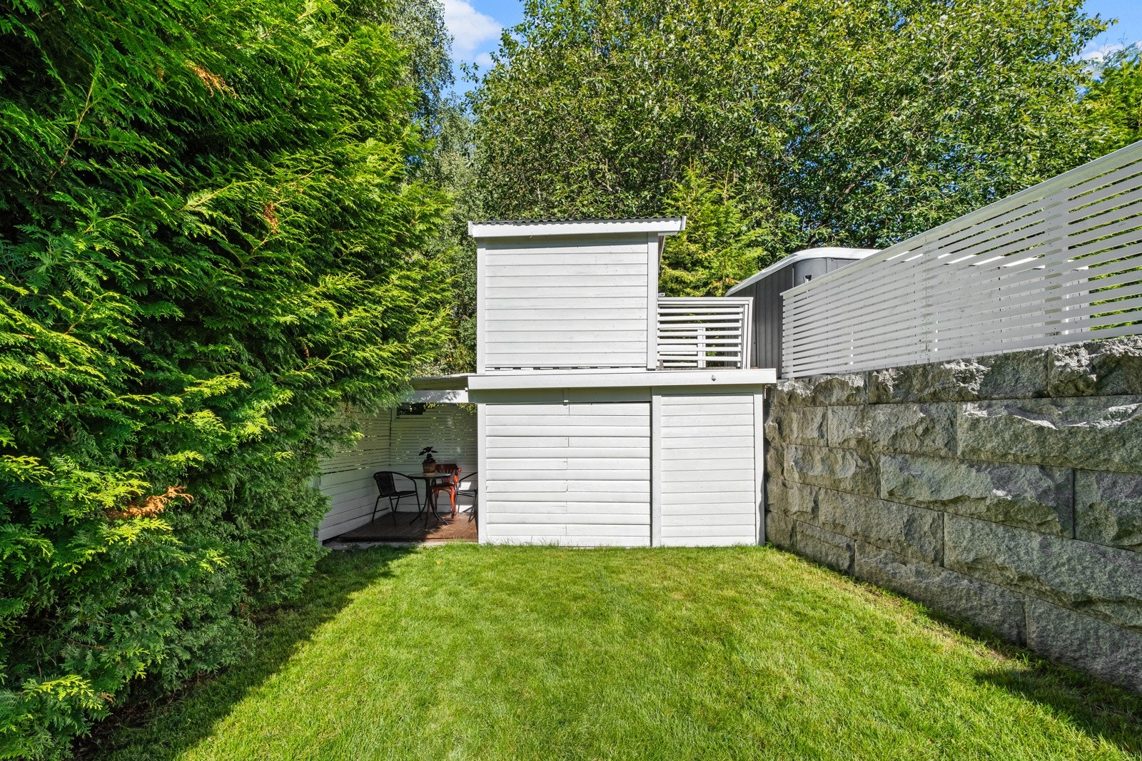 Uteområdet skjermes av tettvokst hekk og frodige trær, både langs tomtegrensen i vest og nord. Galleribilde
