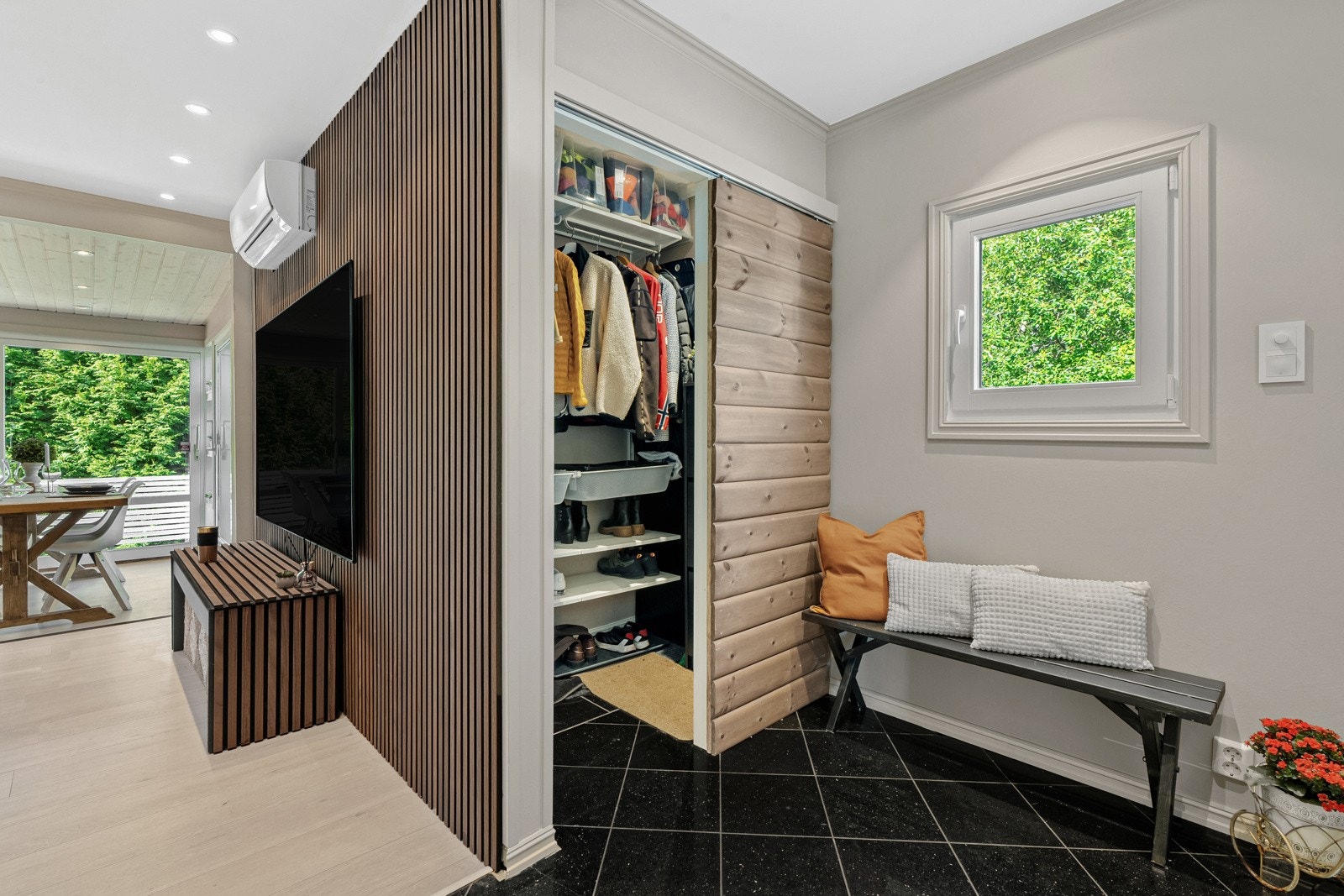 ntréen gir et stilrent førsteinntrykk, med garderoben skjermet av en elegant skyvedør kledd i mørkbeiset panel - en detalj som gjenspeiles flere steder i interiøret. Galleribilde