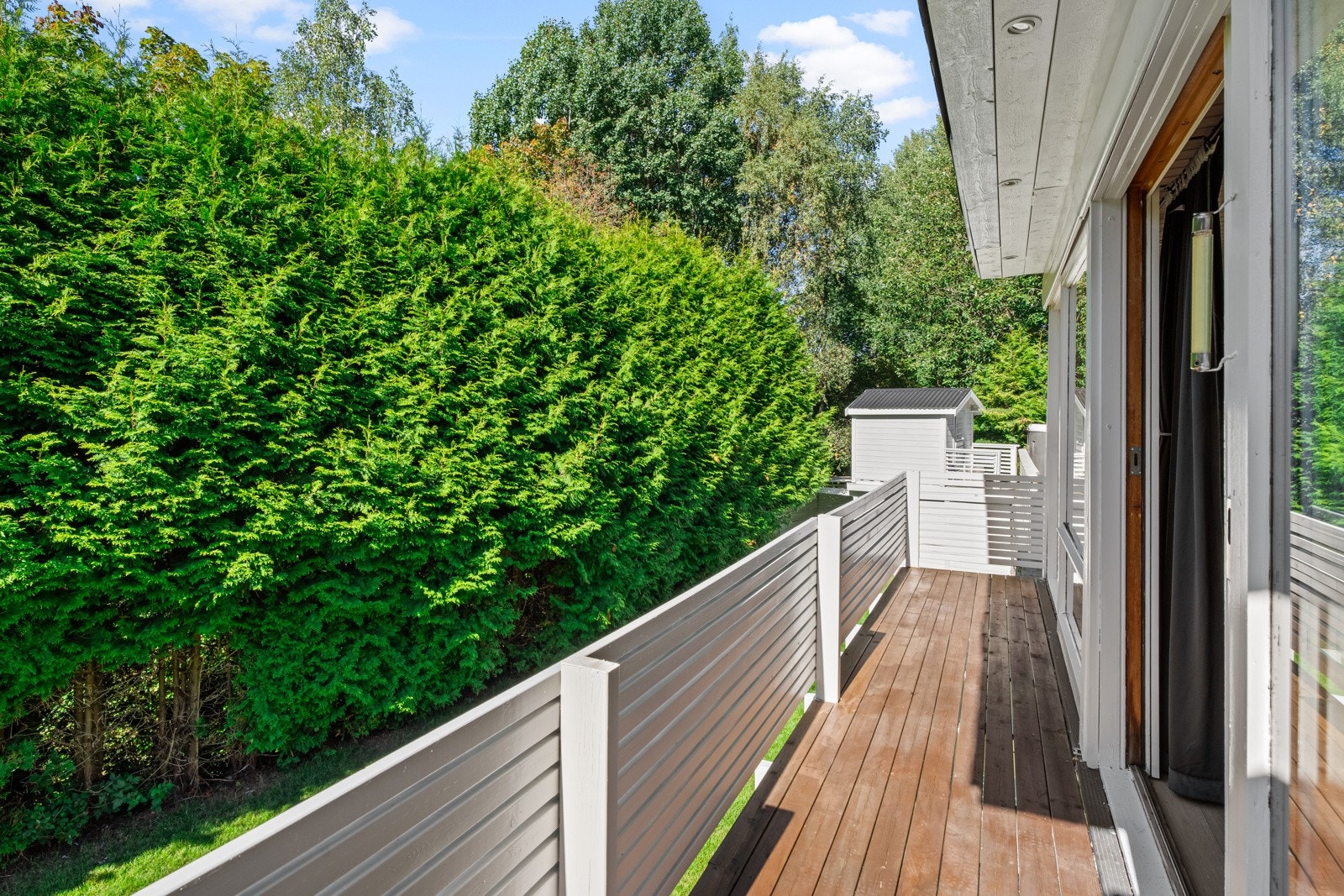 Terrassen har hvitmalt rekkverk og dekke av terrassebord. Galleribilde