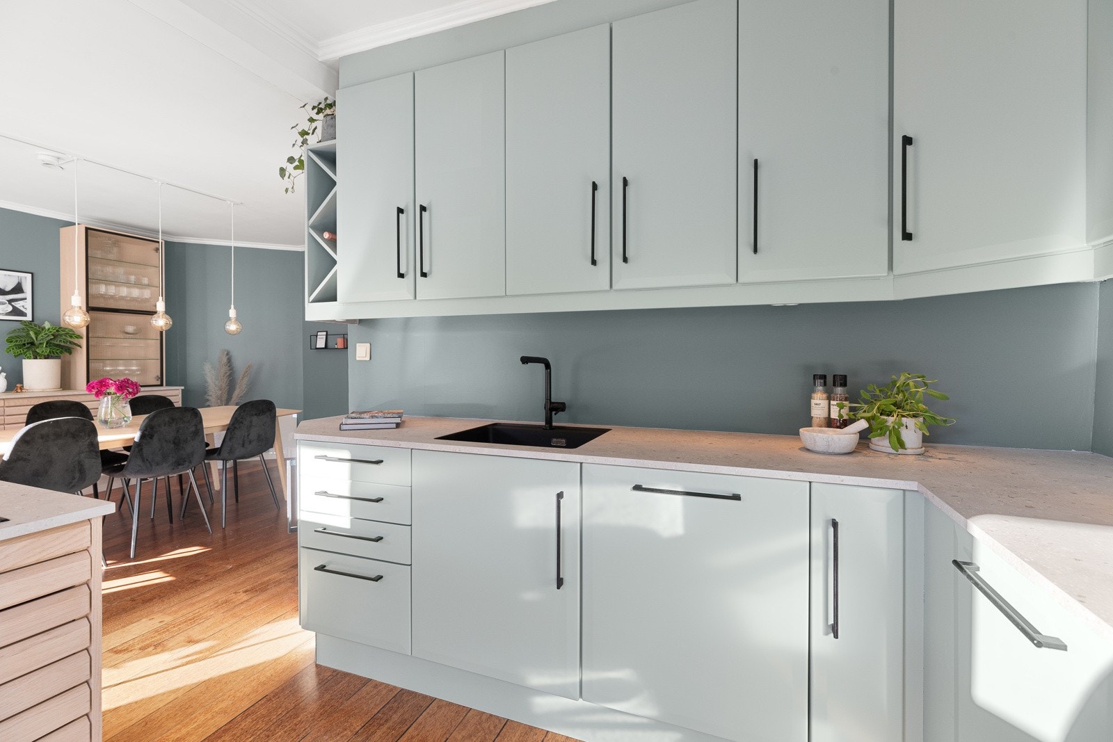 Kjøkkeninnredningen består av lakkerte fronter, sorte håndtak og overskap med benkebelysning. Galleribilde