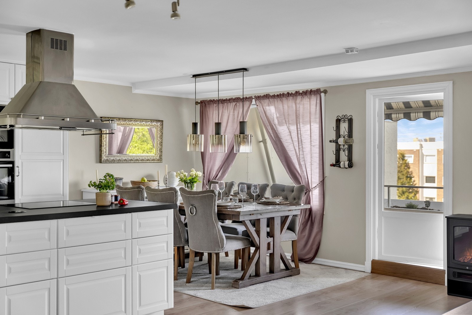 En stor kjøkkenøy med kullfilterventilator i børstet stål, markerer skillet mellom sonene og gir ekstra skap- og benkeplass. Galleribilde