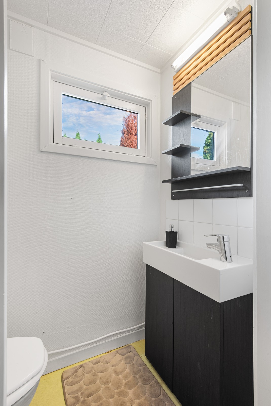 Toalettrommet har gulvfestet toalett, nyere skapinnredning med nedfelt servant og speil med hyller og lysarmatur. Galleribilde