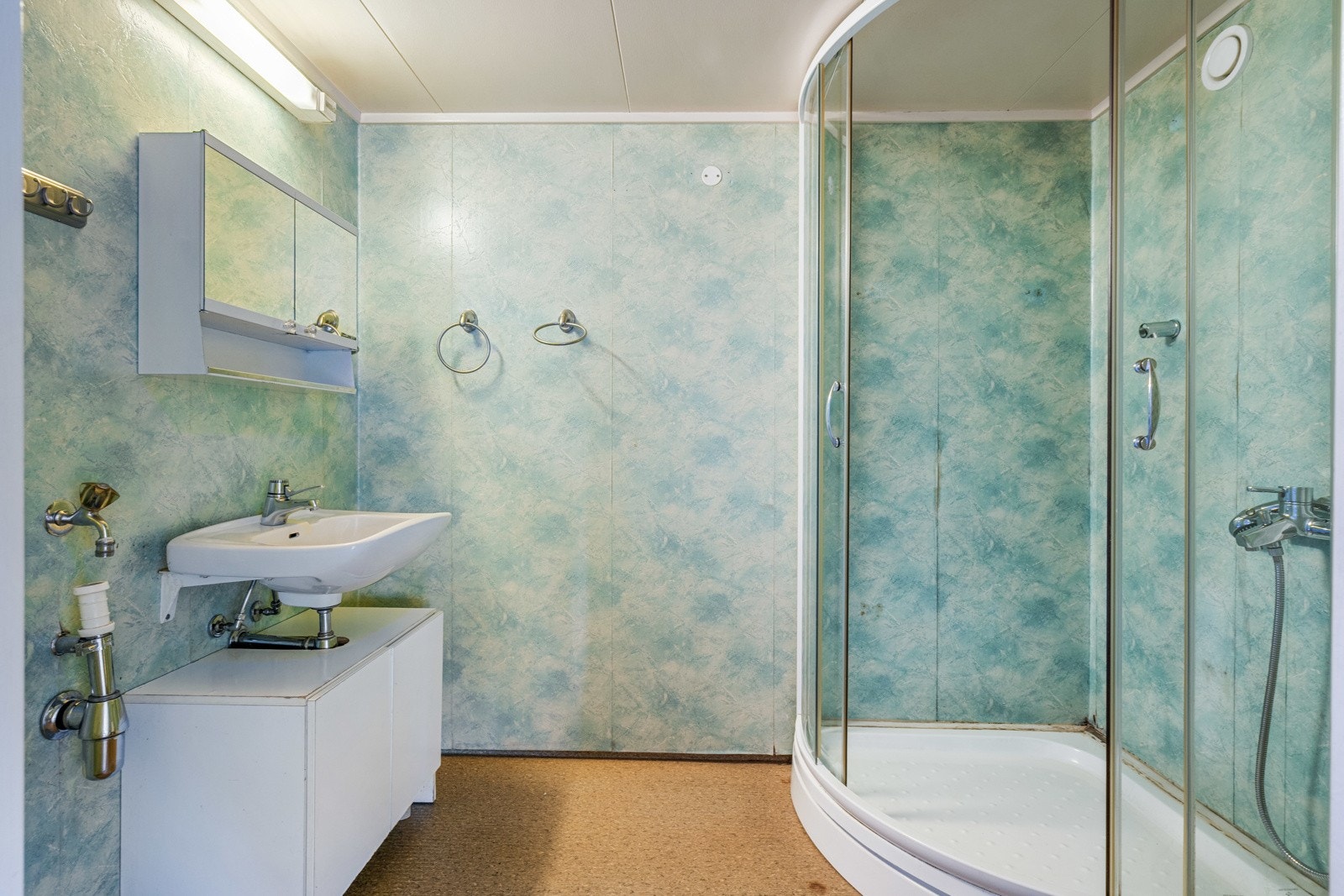 Badet er innredet med baderomsinnredning, vask, speilskap, dusjkabinett og gulvmontert toalett. Galleribilde