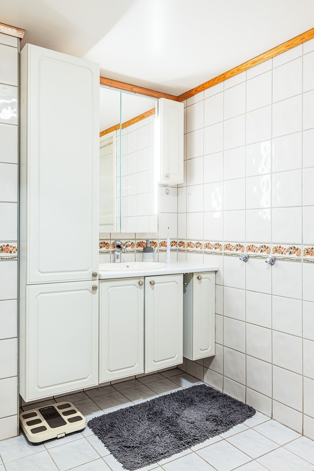 Tidløs baderomsinnredning med lyse fronter og benkeplate med nedfelt servant. I 2023 ble det montert nytt speilskap med LED-belysning over servanten. Galleribilde