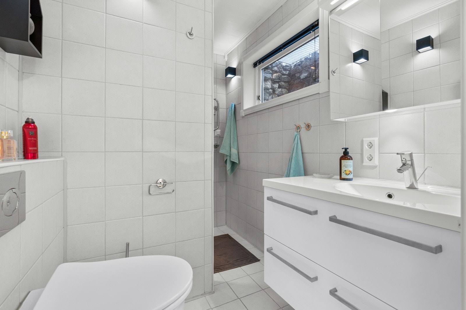 Pent, flislagt bad i kjelleren med varmekabler. Badet er innredet med dusj, vegghengt toalett, servant med skuffeinnredning og speilskap. Galleribilde