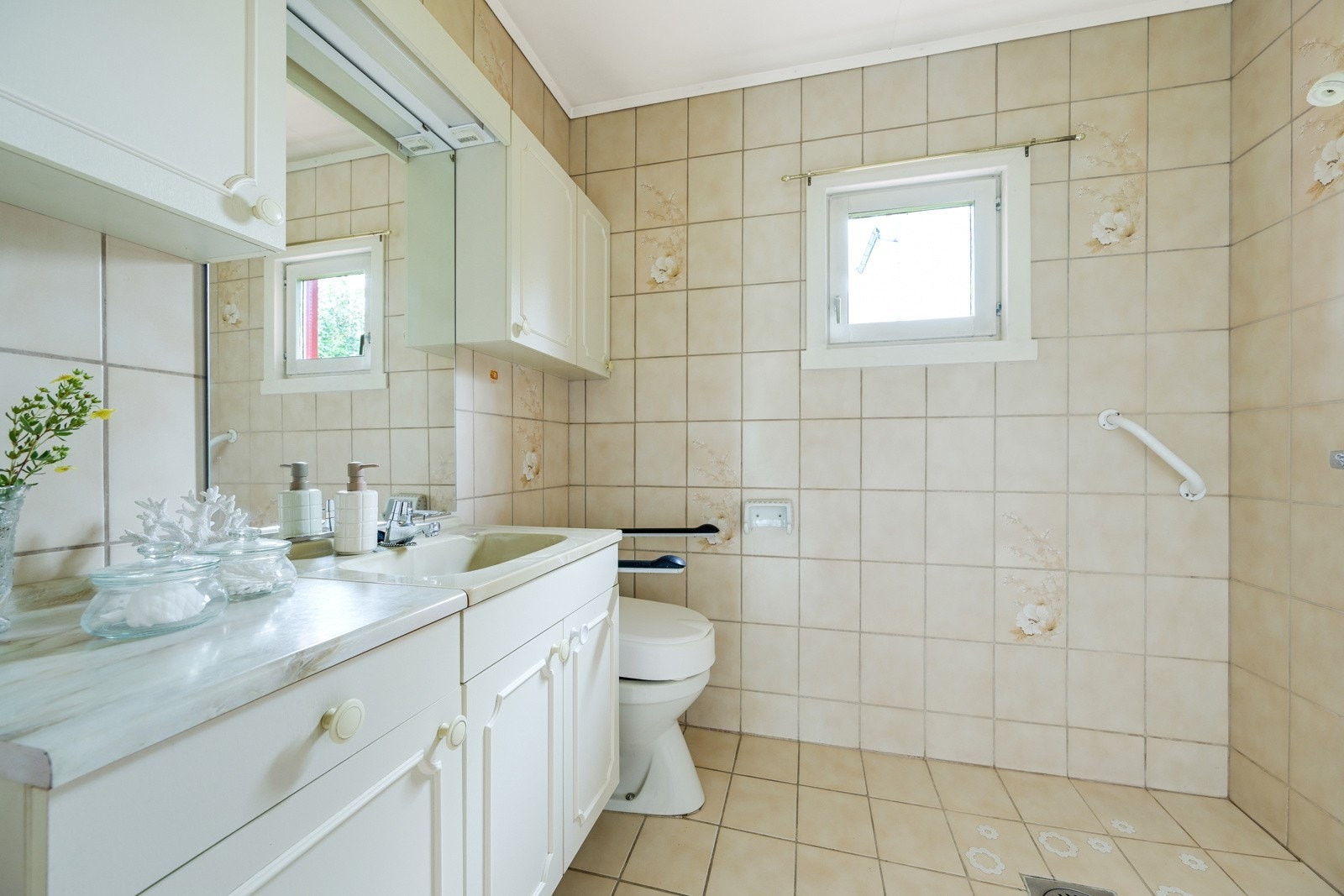 Flislagt bad innredet med dusj, klosett og baderomsinnredning. Galleribilde